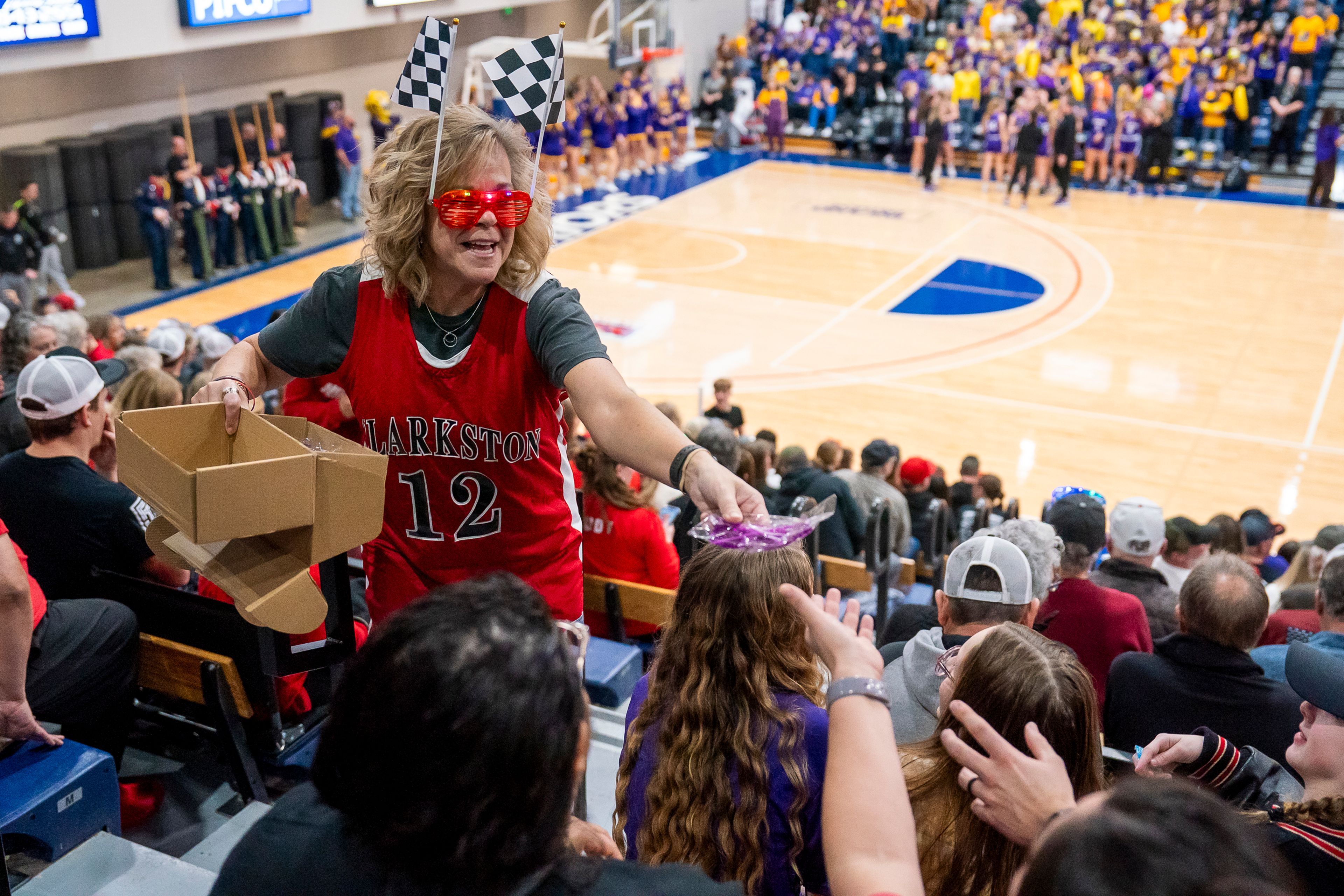 Clarkston High School Assistant Principal Heather Lang hands out glasses before their girls basketball Golden Throne rivalry game against Lewiston on Friday inside the P1FCU Activity Center in Lewiston.