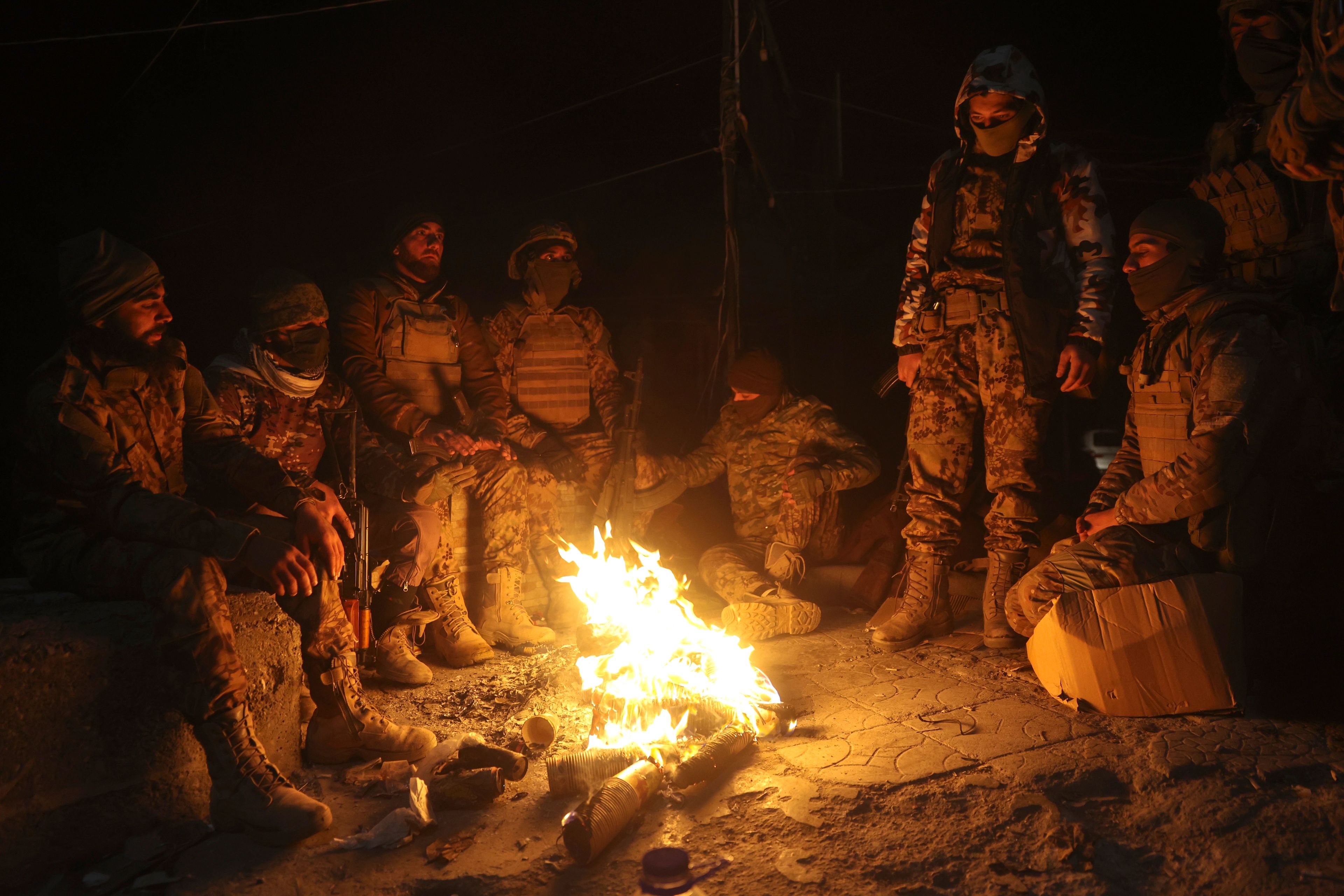 Syrian opposition fighters warm themselves by a fire in the streets of Aleppo, late Friday Nov. 29, 2024. (AP Photo/Ghaith Alsayed)