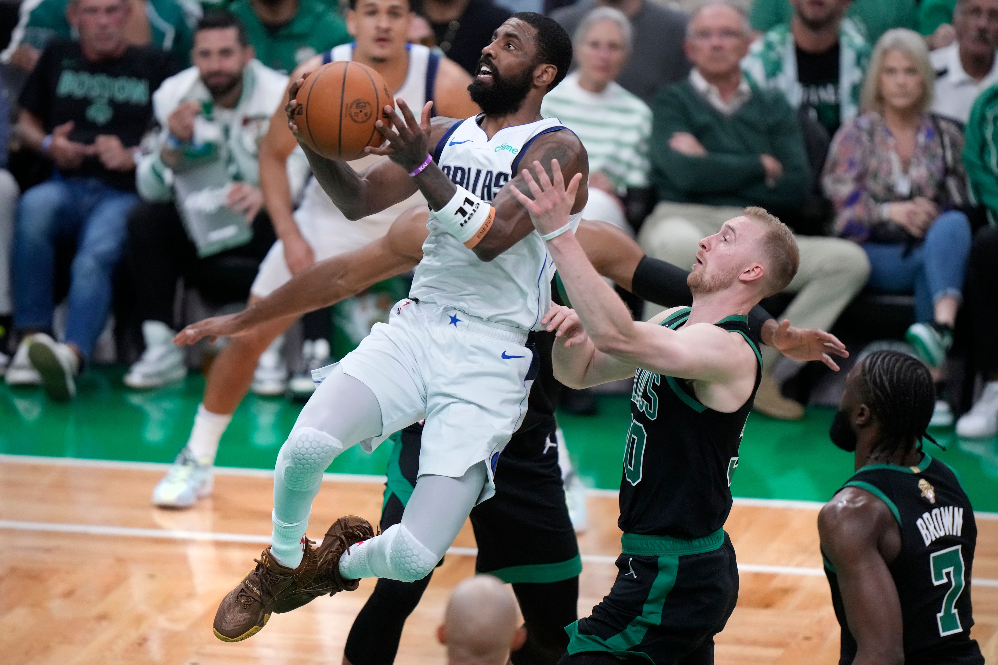 Dallas Mavericks guard Kyrie Irving, front left, drives to the basket past Boston Celtics forward Sam Hauser, second from right, during the first half of Game 2 of the NBA Finals basketball series, Sunday, June 9, 2024, in Boston.