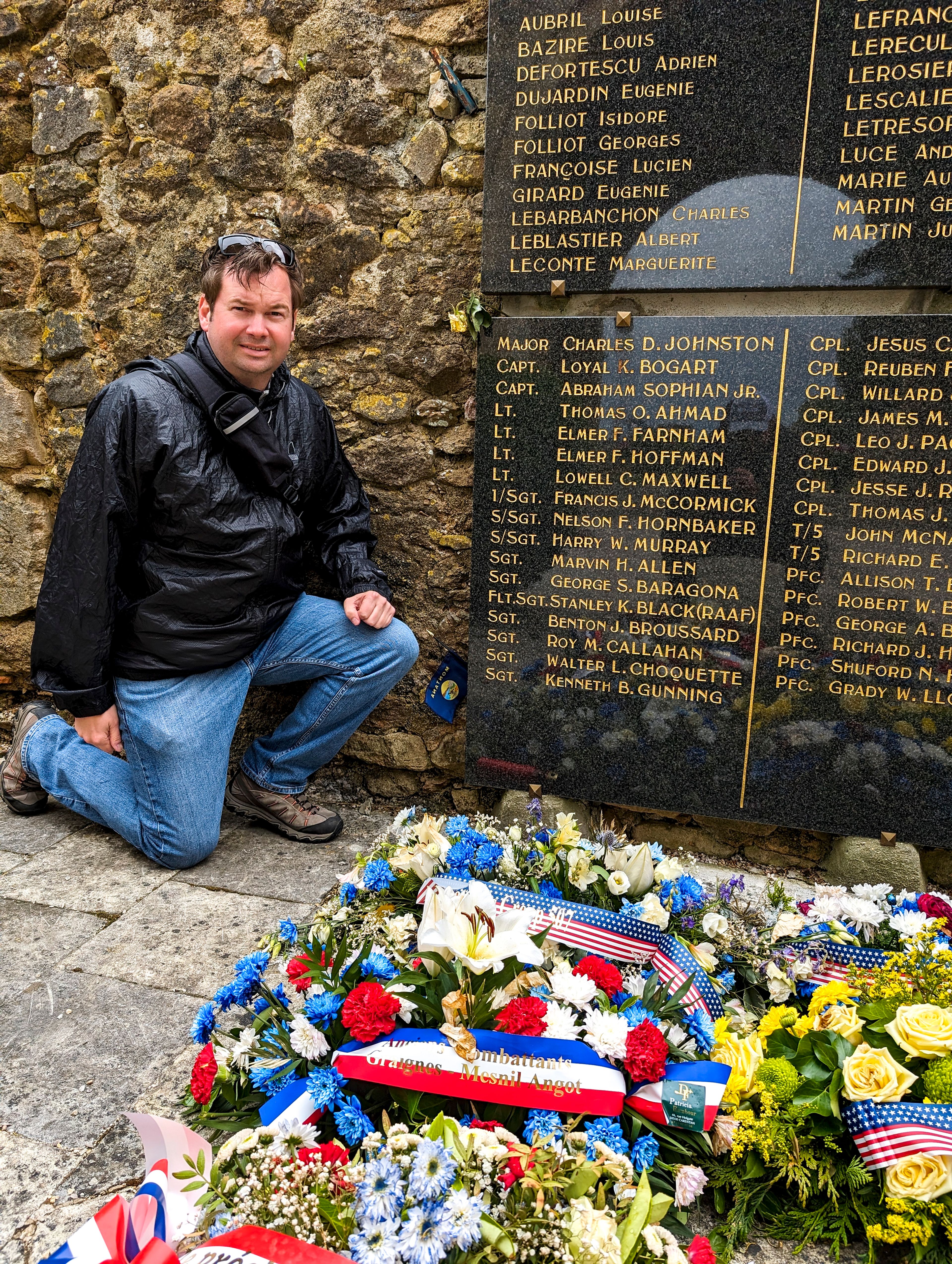 Dustin Johnson kneels beside a monument dedicated to the lives lost within the village of Graignes during the battle for Normandy in June 1944.