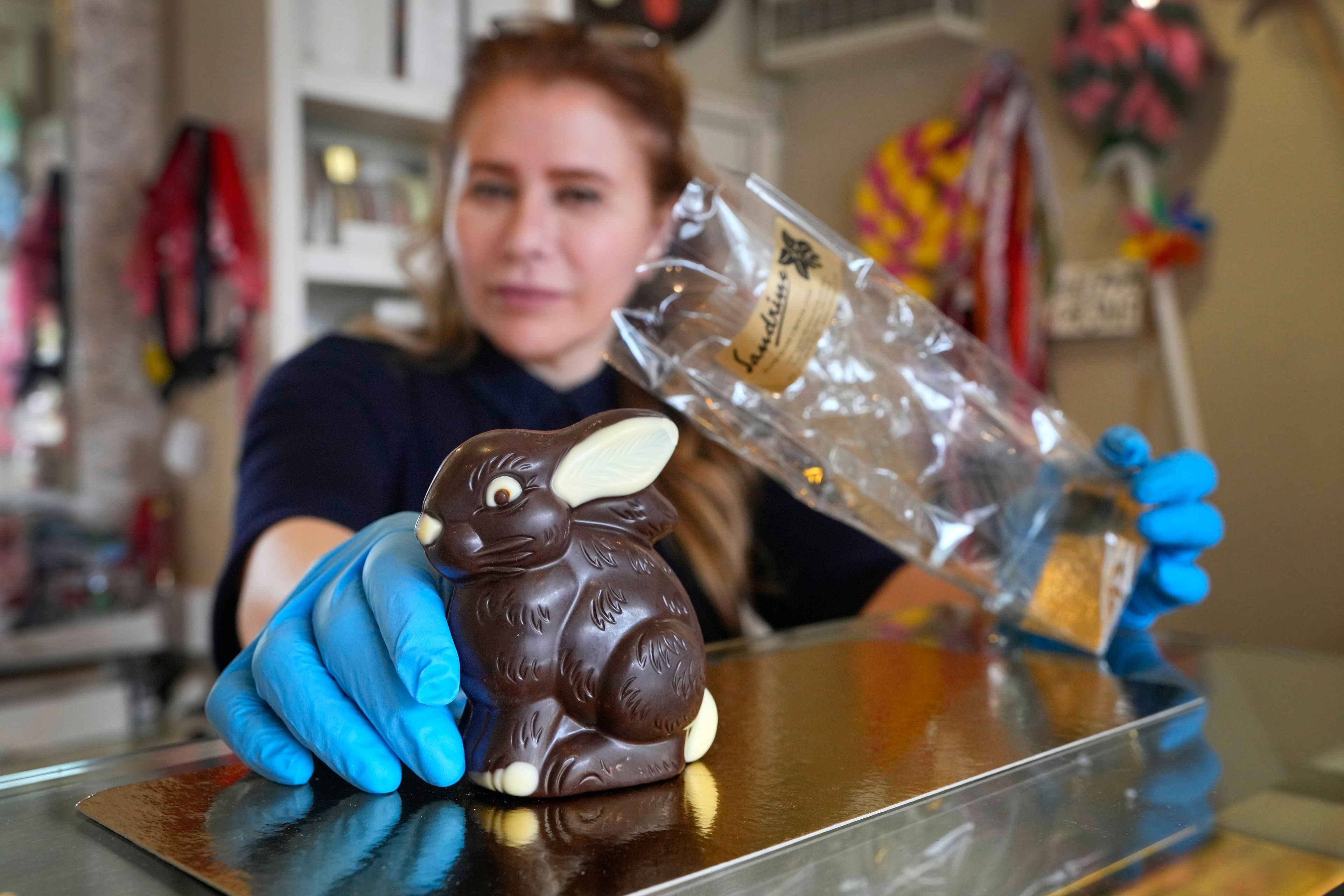 Niaz Mardan wraps a luxury handmade Belgian chocolate rabbit at Sandrine a chocolate shop in south west London, Thursday, March 21, 2024. Niaz Mardan, is suffering due to high cocoa prices, she's making no profits and fears she will have to close the shop that's been around for 25 years (she's the third owner and took over in 2019). (AP Photo/Kirsty Wigglesworth)