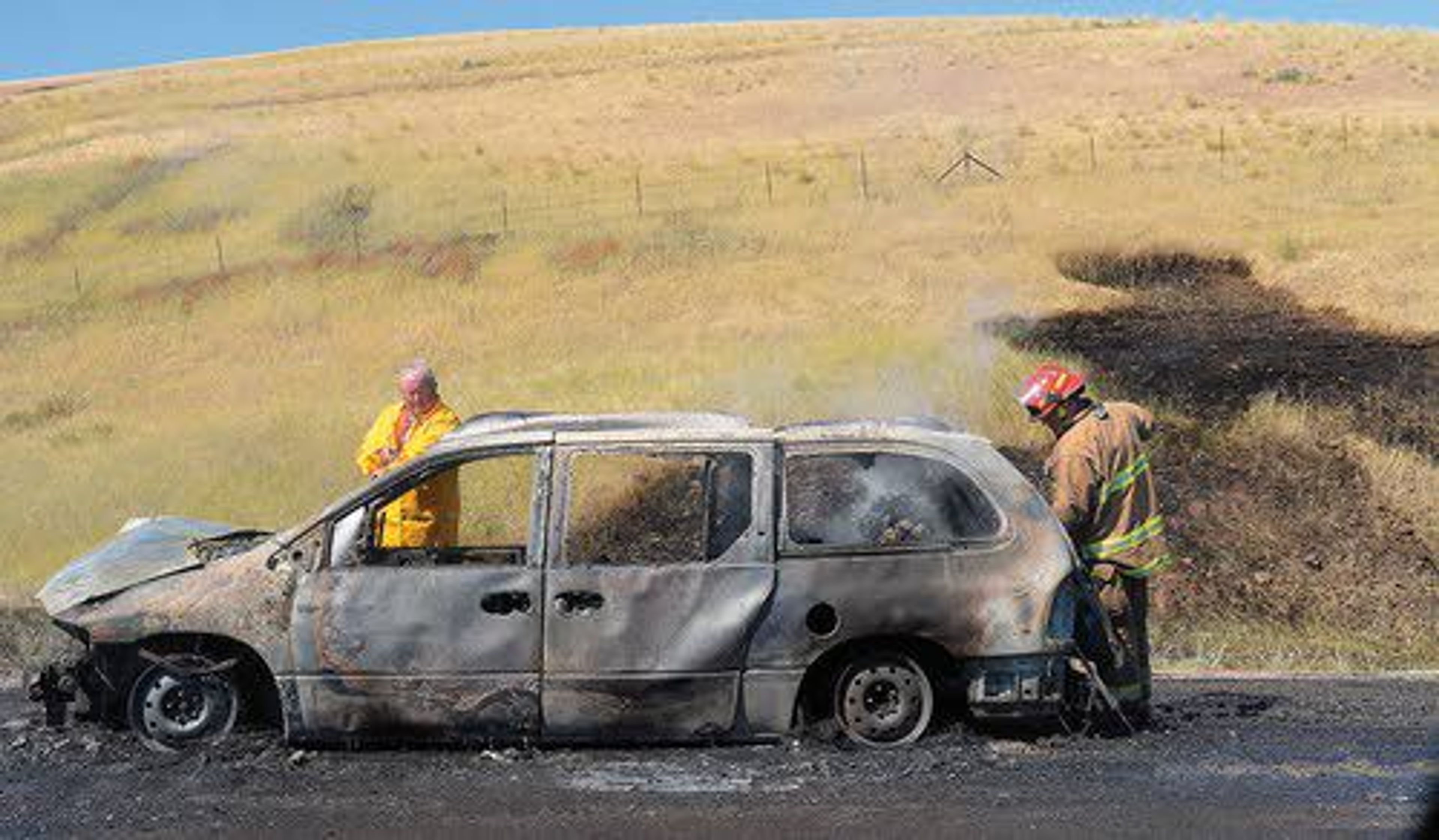 Nez Perce County firefighters extinguish the final embers from a car fire on the Lewiston Hill on Wednesday afternoon. A vehicle overheated and started on fire as it was headed up the hill on U.S. Highway 95 at milepost 315 around 2:30 p.m. No one was injured, but the vehicle was a total loss. Nez Perce County Fire District and Idaho State Police responded. Fire District Chief Ron Hall said three engines responded to the fire and were able to douse the vehicle as well as a grass fire that started nearby. Hall said about a quarter-acre of grass was burned.