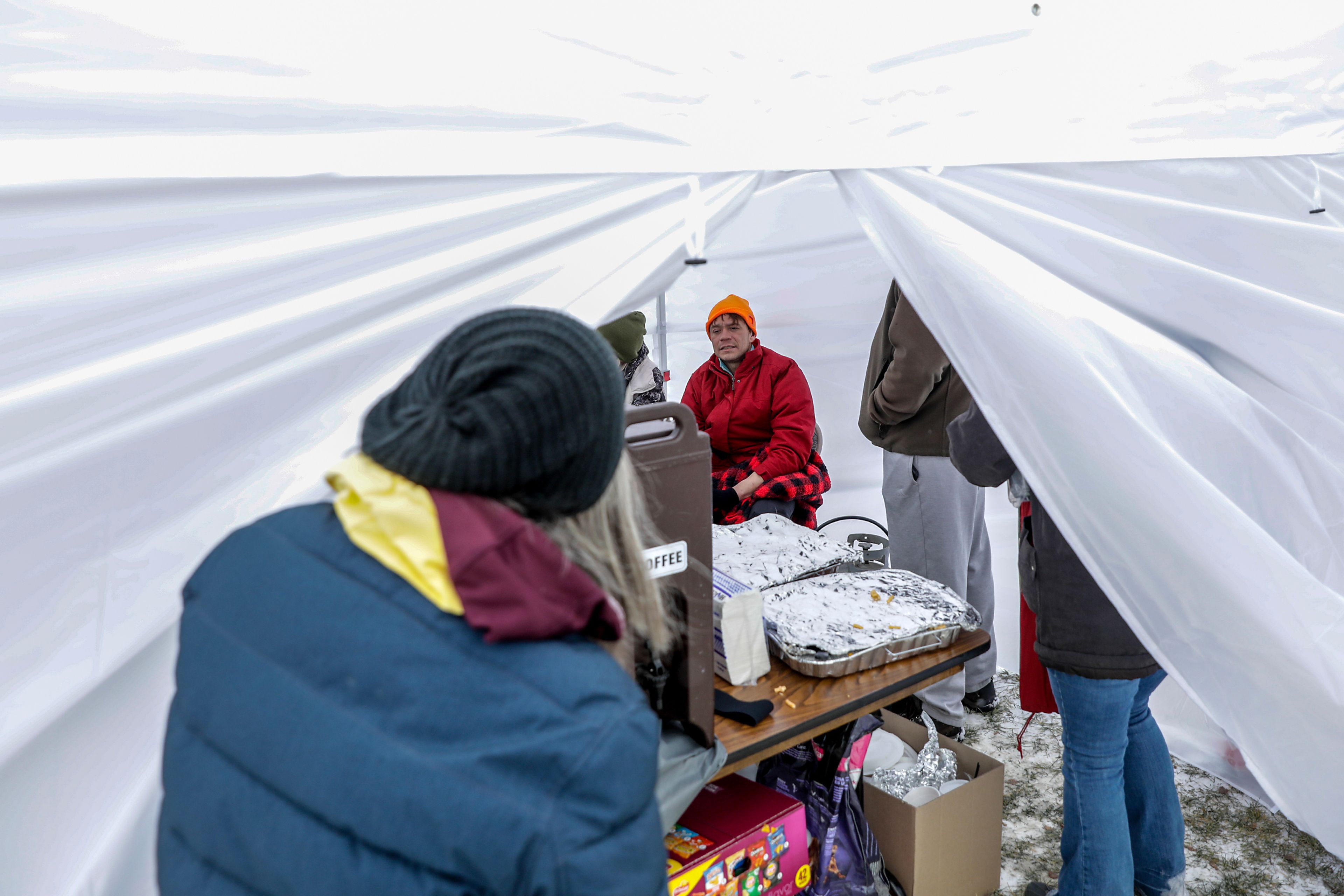 Rocky, a resident of the homeless camp behind Walmart, warms up inside a tent outside the Chef Store Sunday in Clarkston.