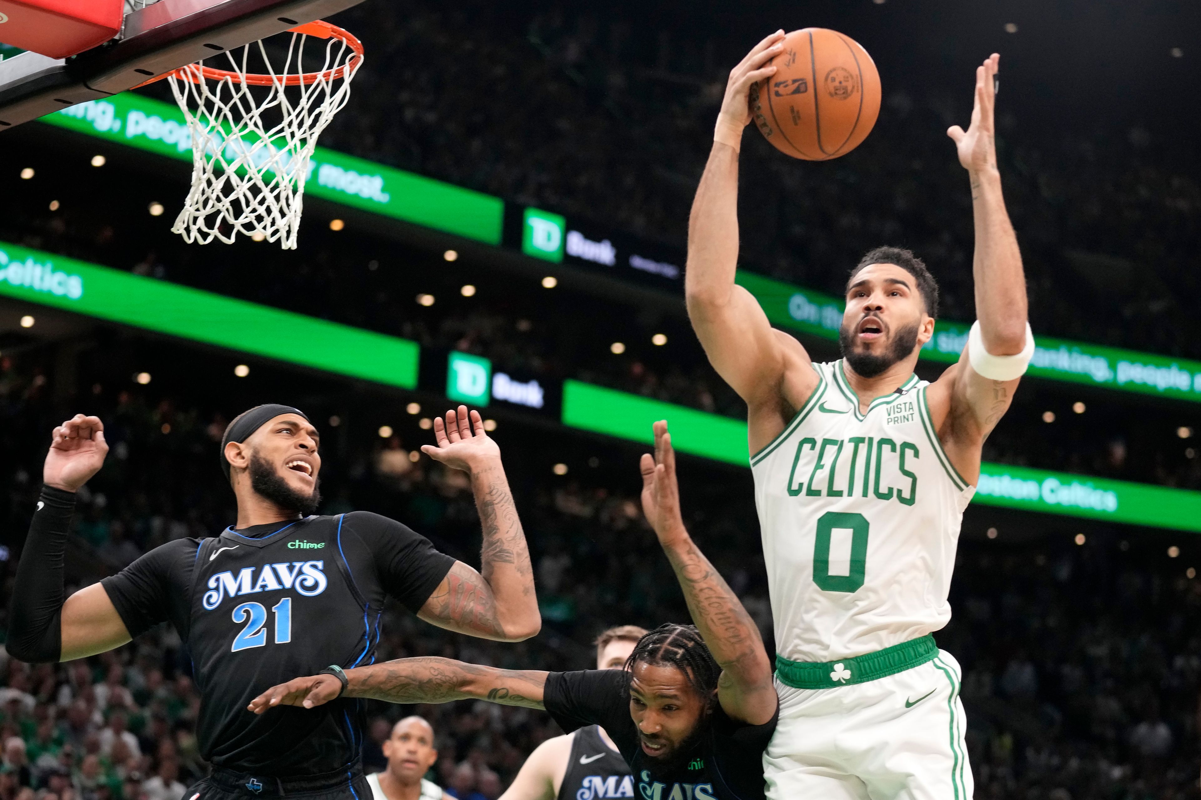 Boston Celtics forward Jayson Tatum, right, drives toward the basket as Dallas Mavericks center Daniel Gafford, left, and forward Derrick Jones Jr., below, defend during the first half of Game 1 of basketball's NBA Finals on Thursday, June 6, 2024, in Boston.