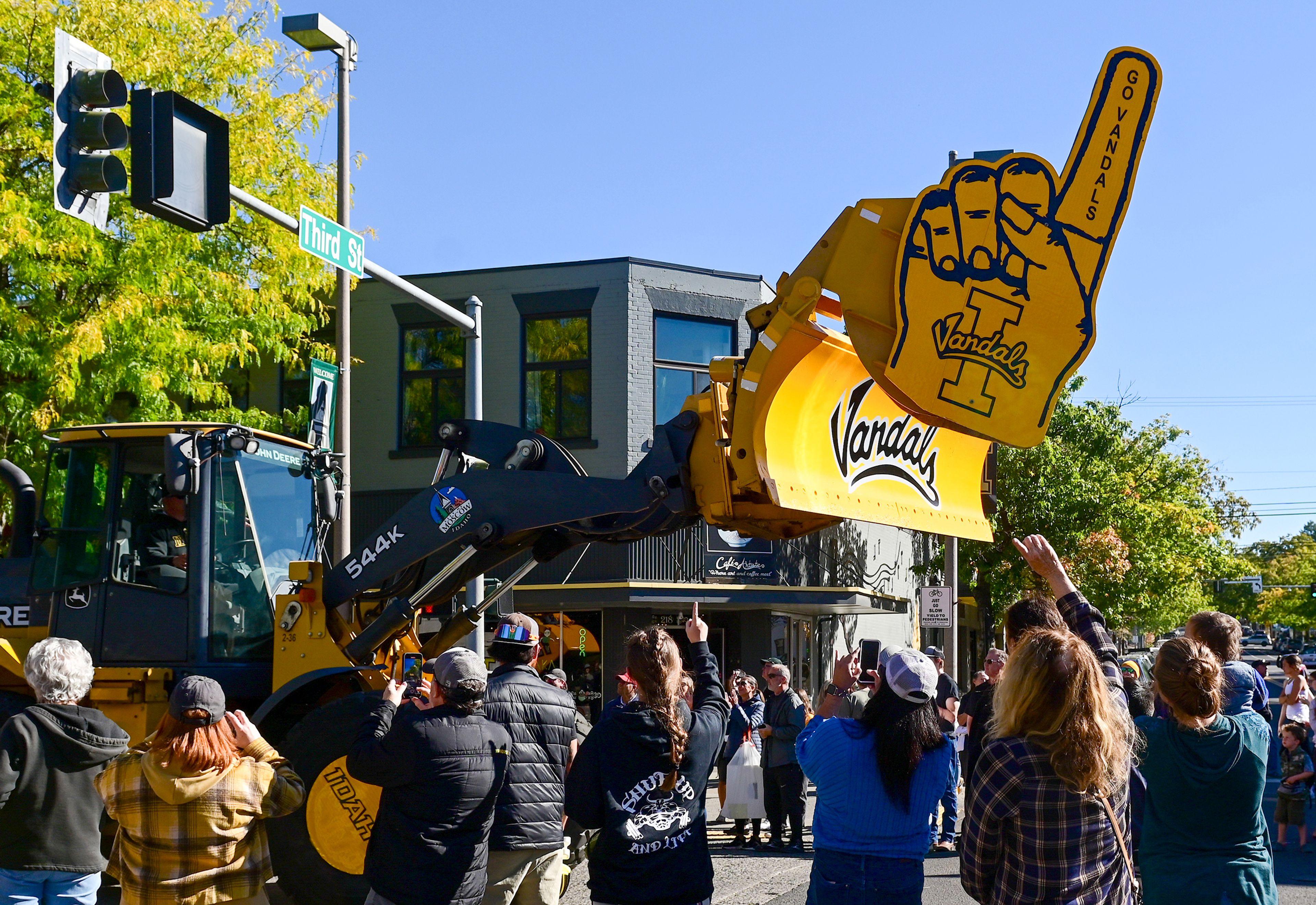 Those watching the parade raise their hands to match the giant foam finger attached to a bulldozer in the homecoming parade Saturday in Moscow.