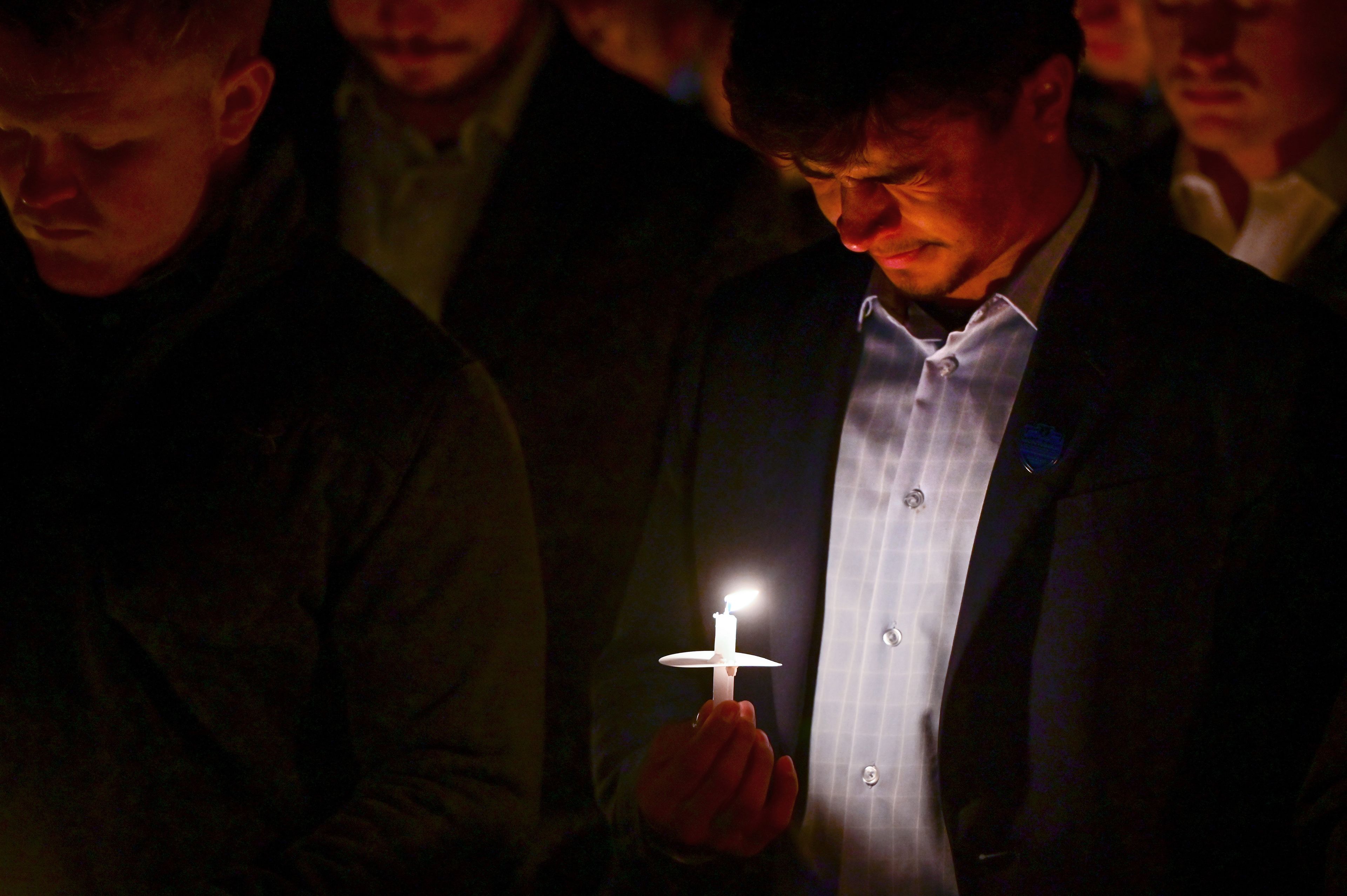 Those gathered for a vigil in honor of the four University of Idaho students killed a year ago look down at their candles, with some holding back tears, during a moment of silence after hearing a friend speak about each student killed—Ethan Chapin, Xana Kernodle, Madison Mogen and Kaylee Goncalves.