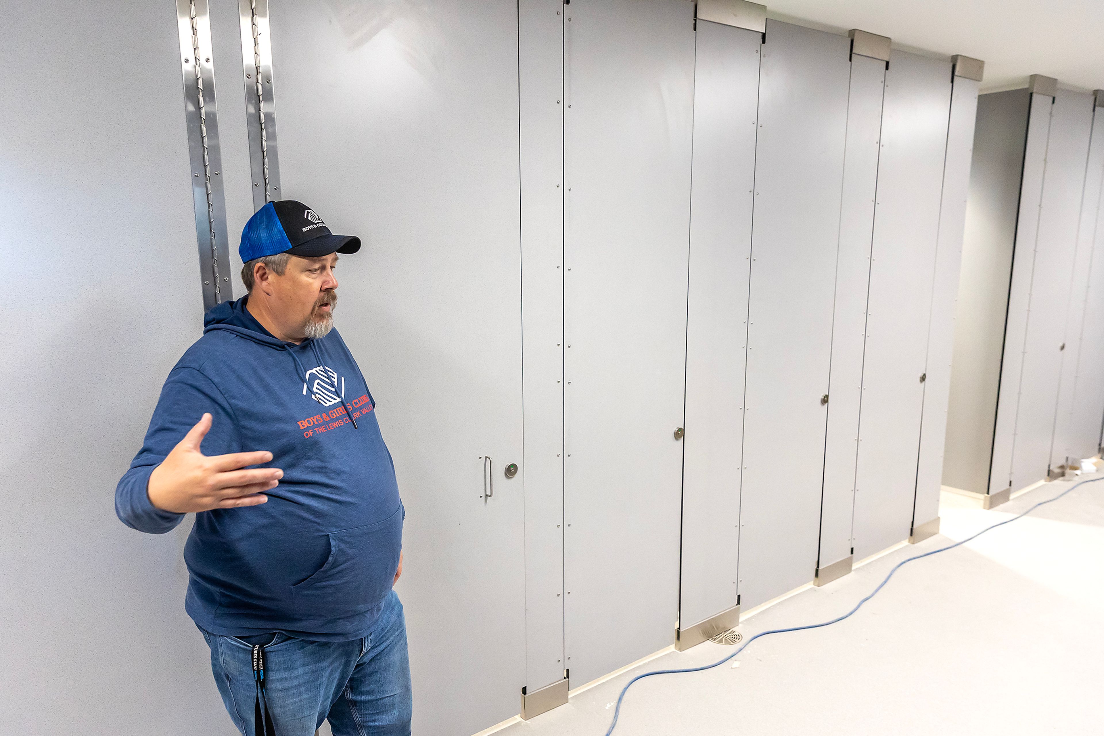 Jon Evans stands next to bathrooms with stalls that go all the way to the top and bottom without gaps in the door at Booth Hall Wednesday in Lewiston