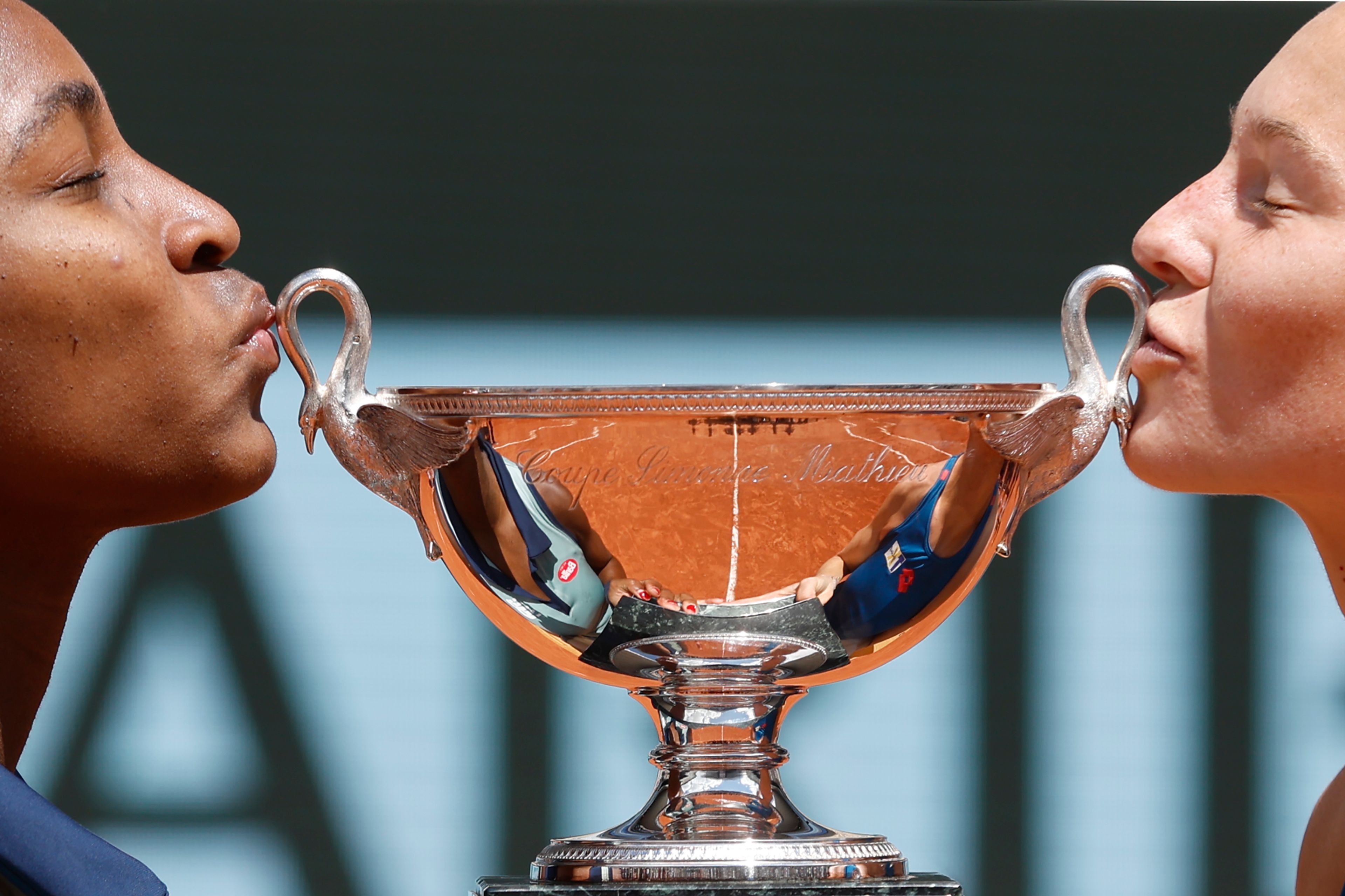 Coco Gauff of the U.S., left, and Katerina Siniakova of the Czech Republic kiss the trophy as they won the women's doubles final match of the French Open tennis tournament against Italy's Sara Errani and Jasmine Paolini at the Roland Garros stadium in Paris, Sunday, June 9, 2024.