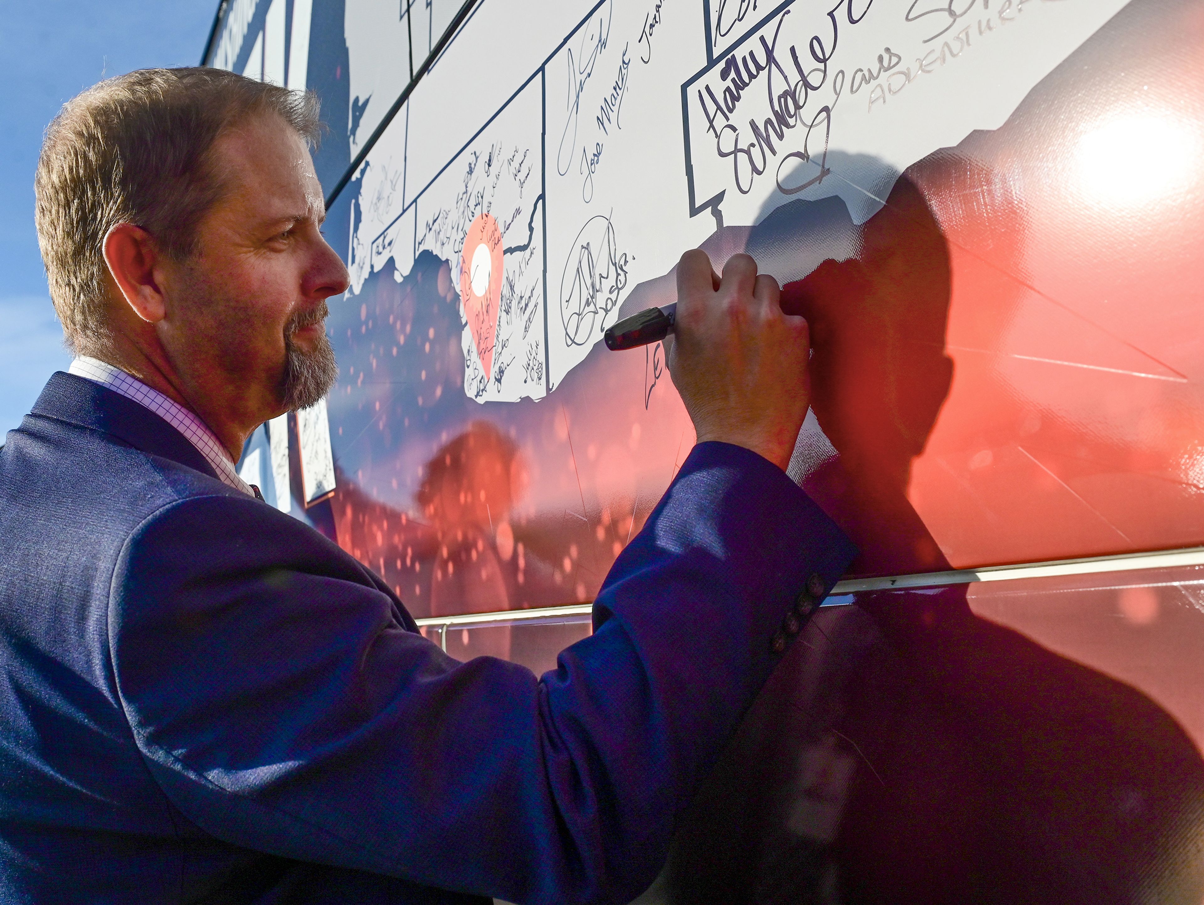 Leith Sorenson, senior vice president of manufacturing at Schweitzer Engineering Laboratories, signs the Association of Washington Business Manufacturing Week bus Thursday at its stop at SEL in Pullman.