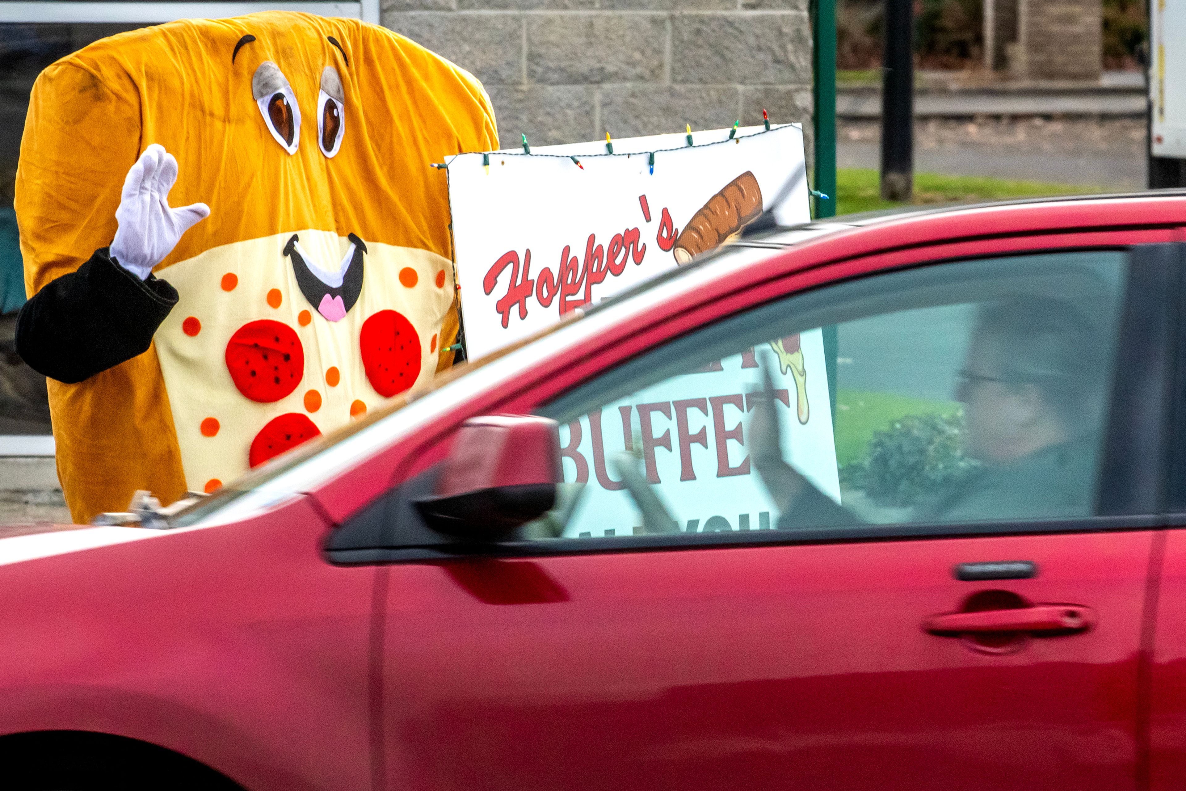 A driver waves to a pizza mascot promoting Hopper’s Pizza Buffet along Main Street Thursday in Lewiston.