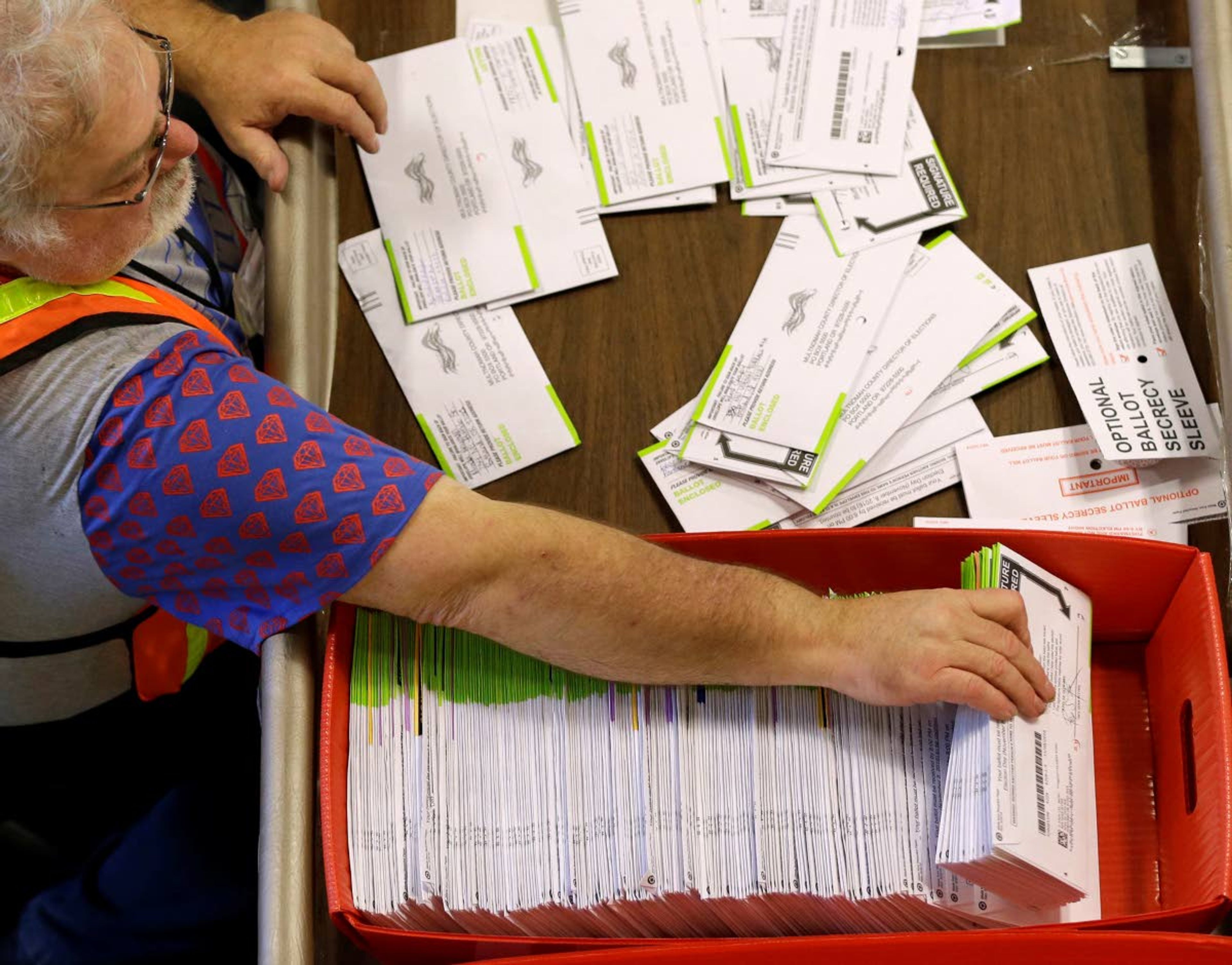 In this Nov. 8, 2016, file photo, election worker Harry Nein processes ballots at Multnomah County election headquarters in Portland, Ore.