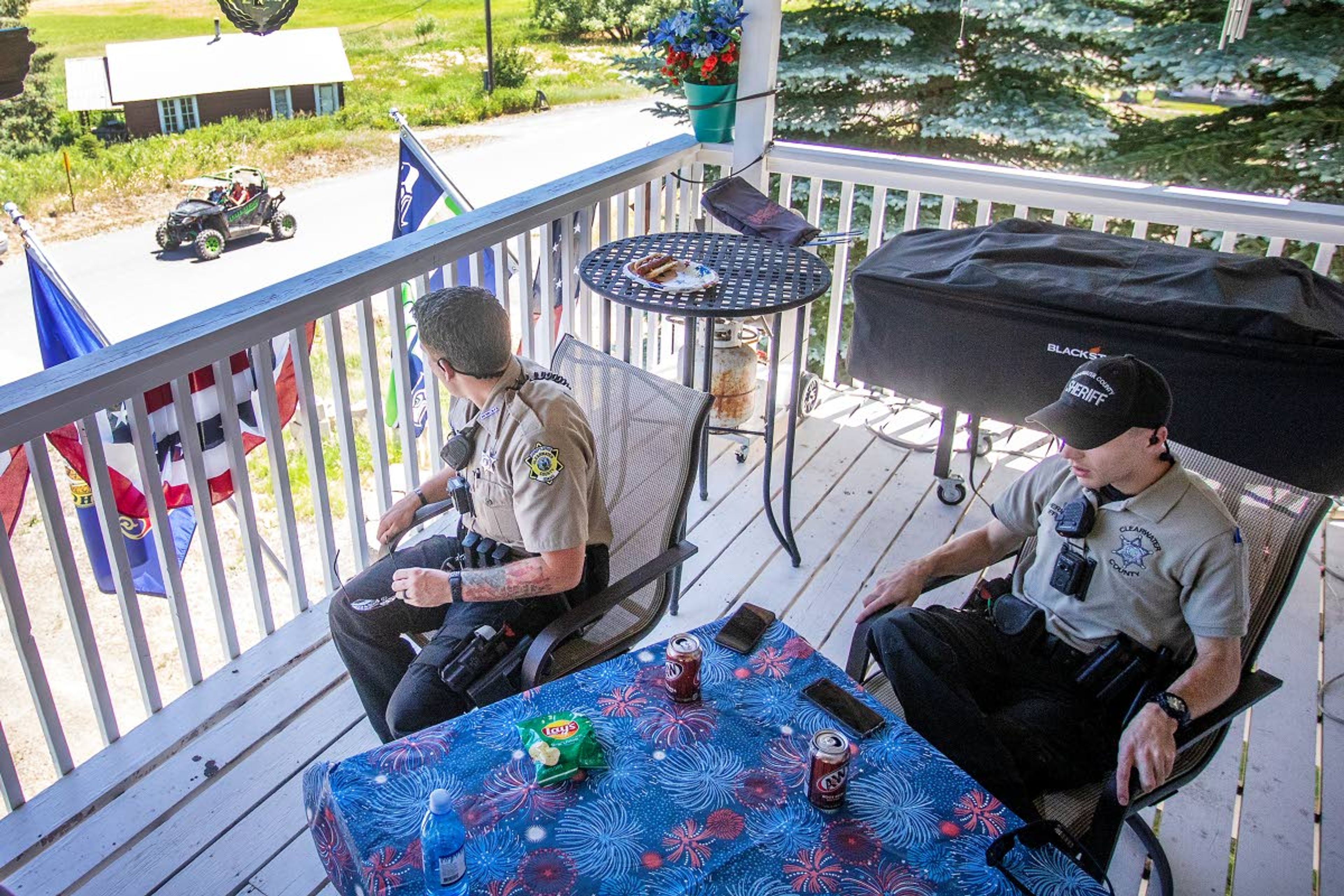 Clearwater County Deputy Kasey Light turns to look at a loud all-terrain vehicle moving down the street as he and Deputy Connor McCullough take a break Saturday on the front deck of Diana and Dave Olson’s Elk River home.