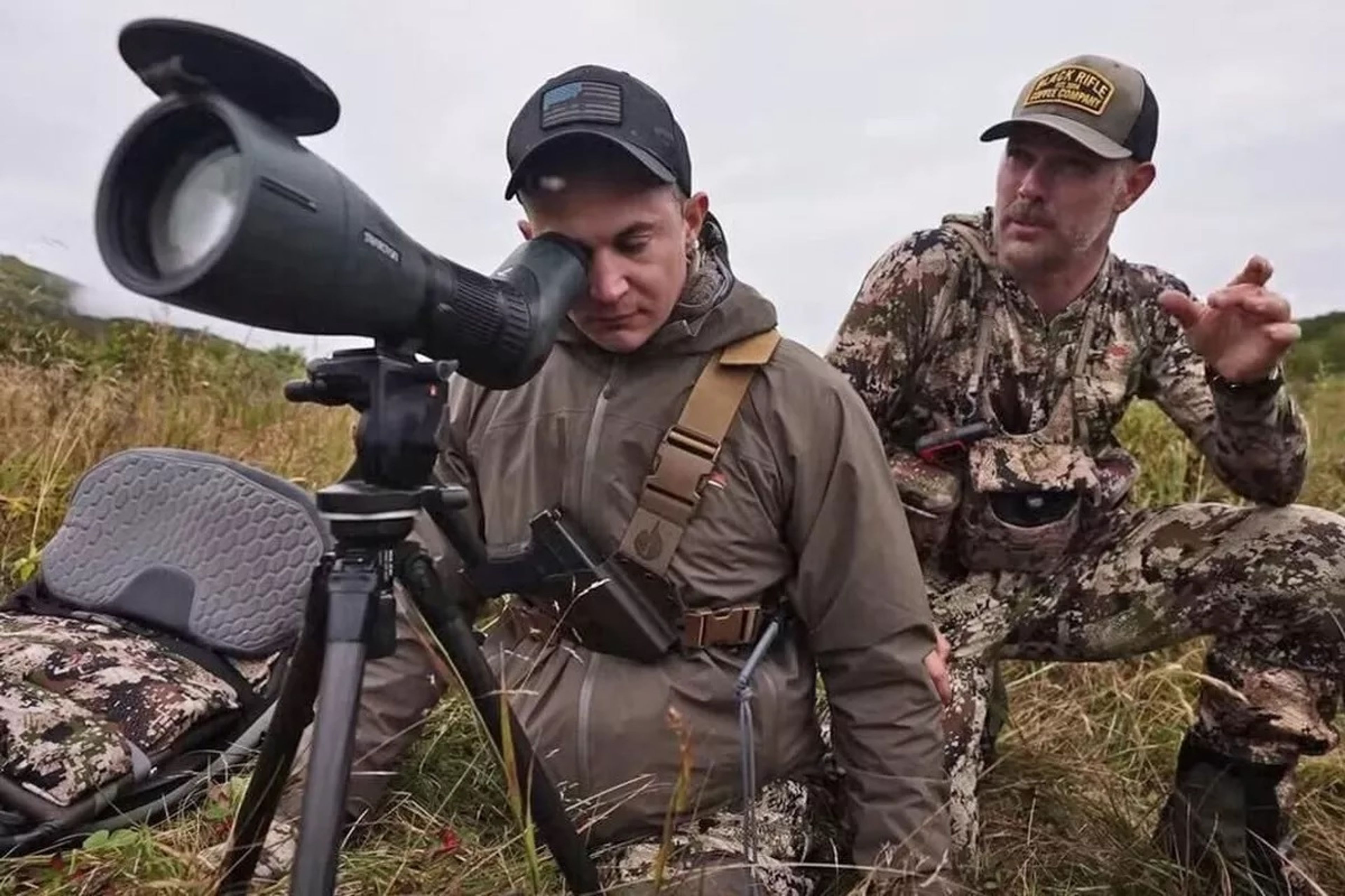 Jonathon Blank looks through a spotting scope as Cole Kramer talks.