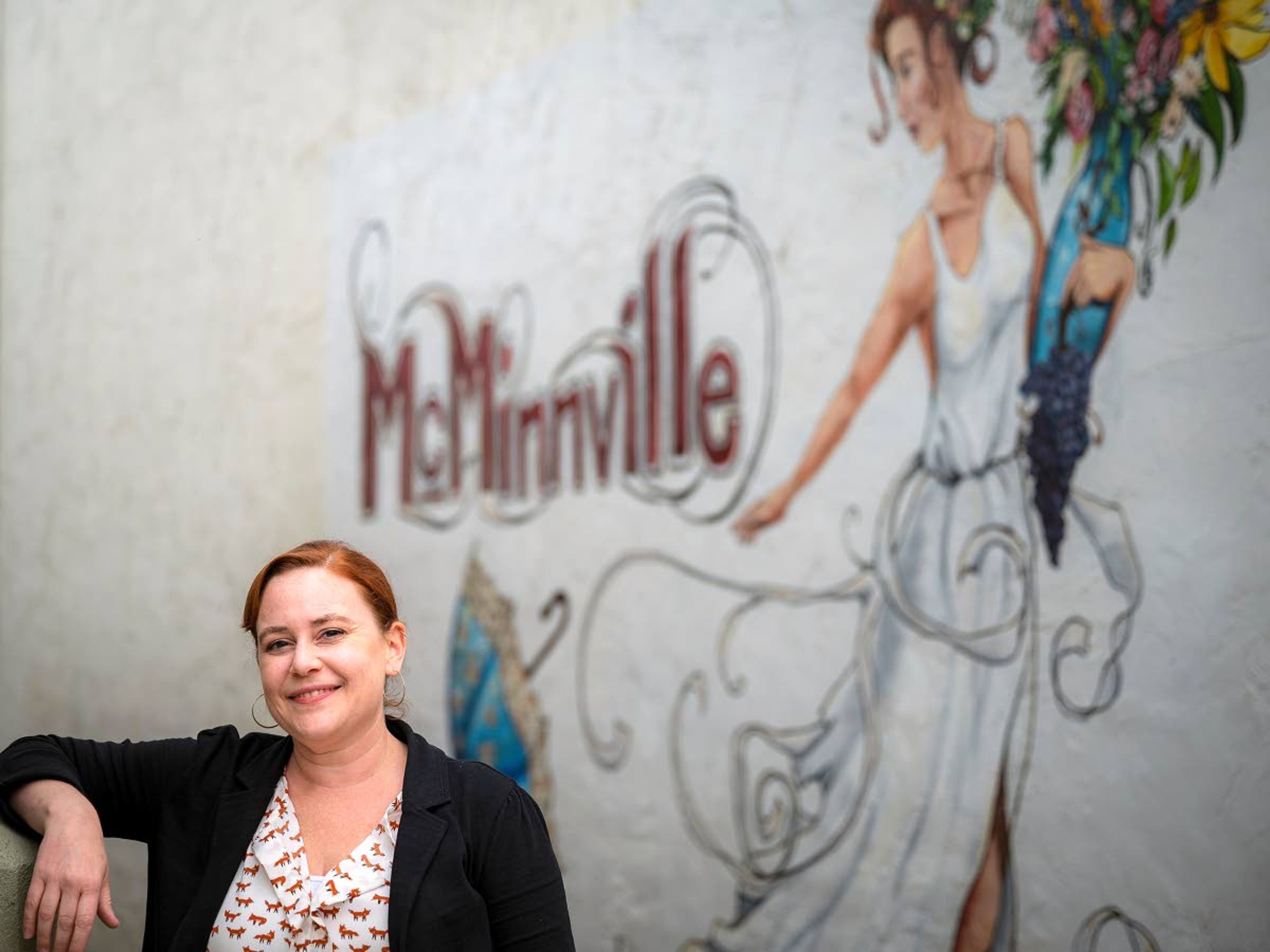 Kitri McGuire, the marketing manager at Visit McMinnville, poses in front of one of murals that color downtown McMinnville.