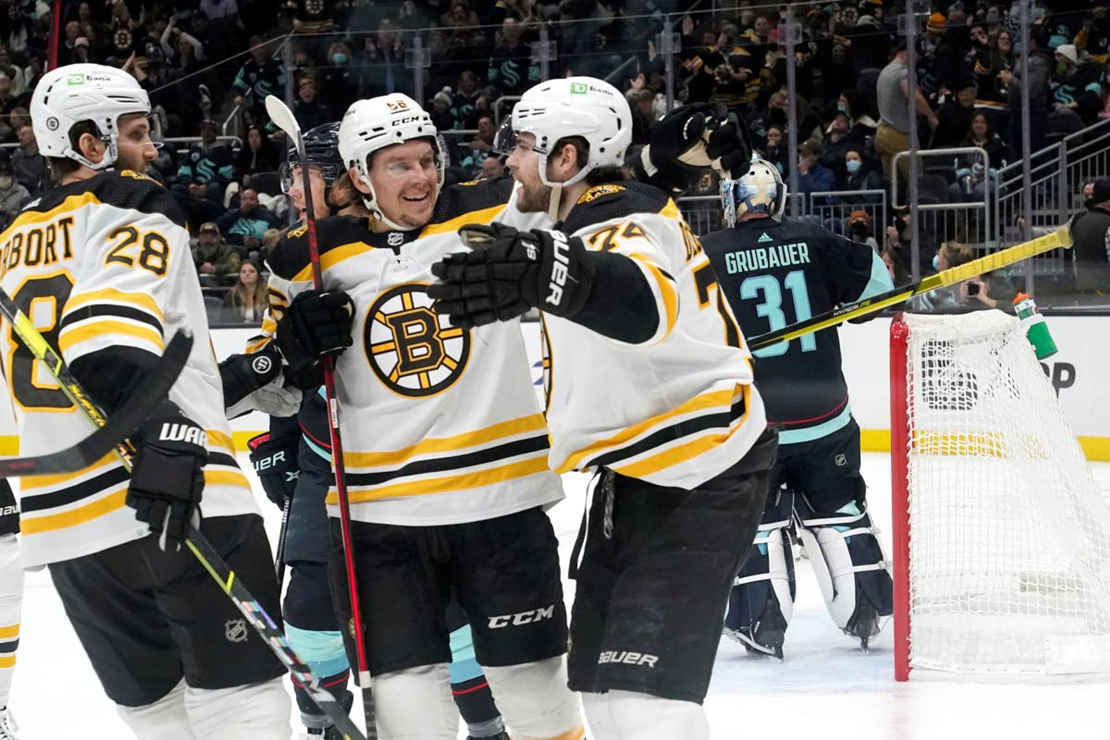 Boston Bruins' Jake DeBrusk, right, is congratulated by teammates Derek Forbort, left, and Erik Haula after scoring against the Seattle Kraken in the first period of an NHL hockey game Thursday, Feb. 24, 2022, in Seattle. (AP Photo/Elaine Thompson)