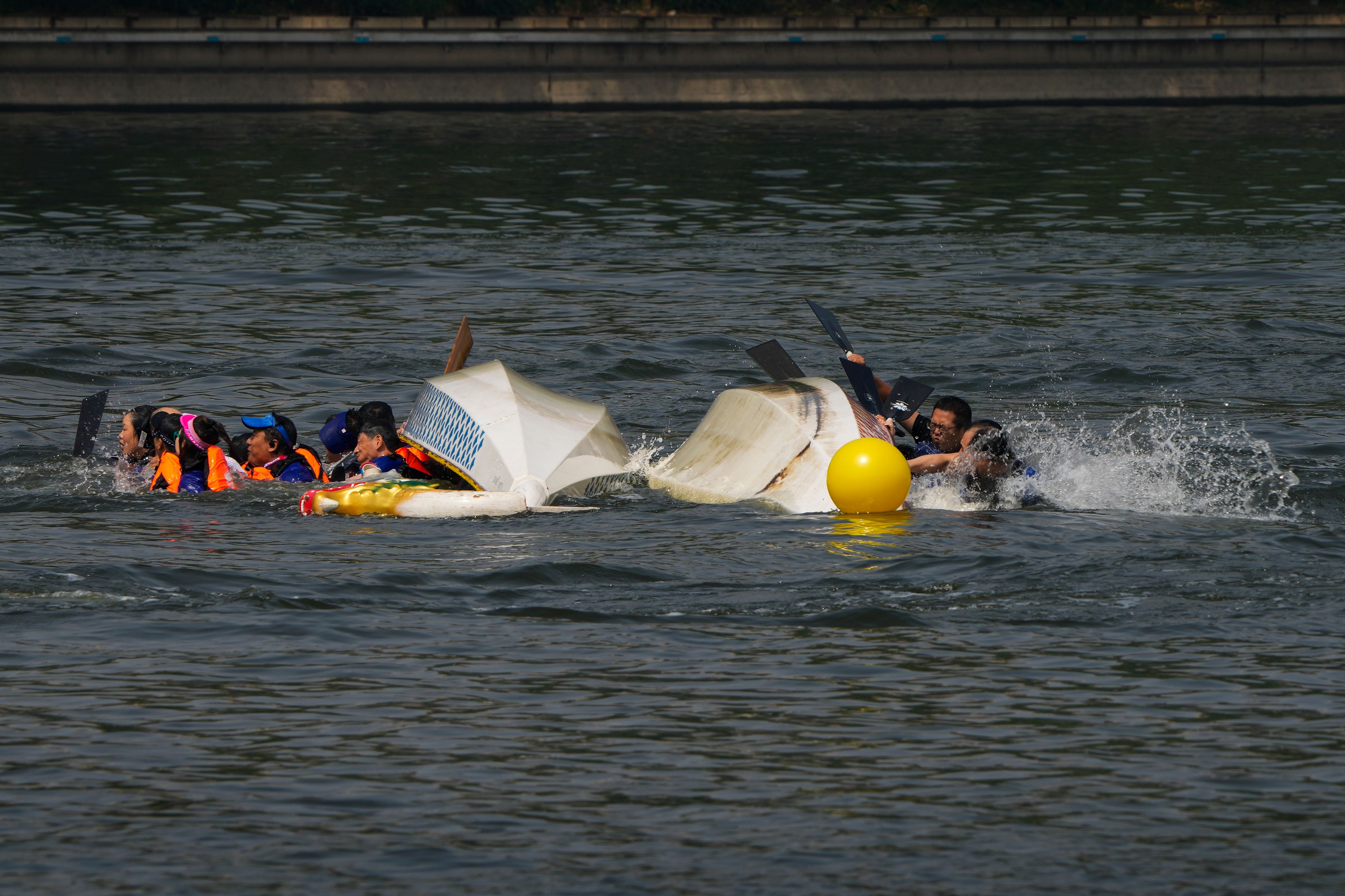 Competitors fall as the boats overturned following a crash during the Dragon Boat Festival at a canal in Tongzhou, outskirts of Beijing, Monday, June 10, 2024. The Duanwu Festival, also known as the Dragon Boat Festival, falls on the fifth day of the fifth month of the Chinese lunar calendar and is marked by eating rice dumplings and racing dragon boats.