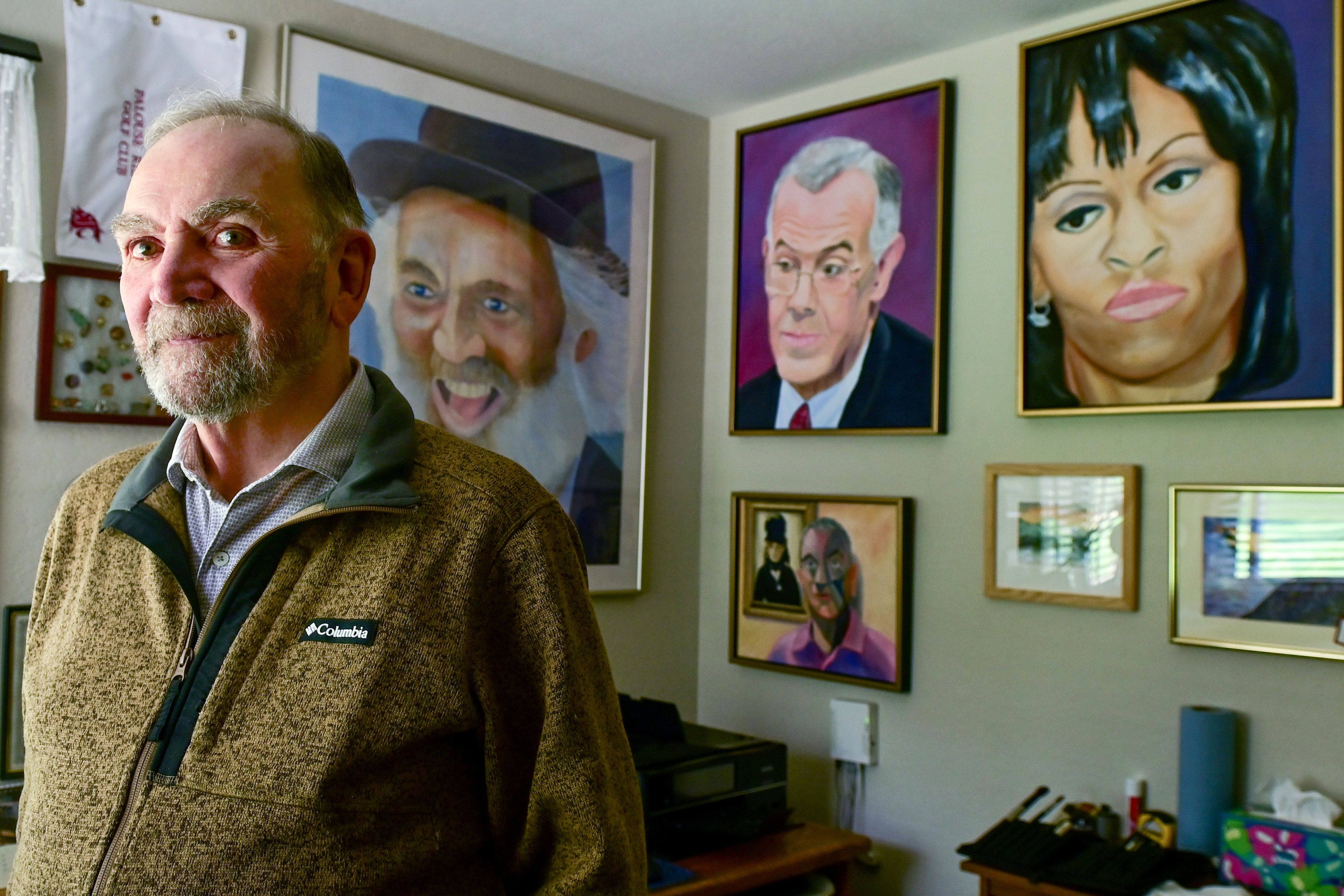 Ernie Weiss, president of the Palouse Watercolor Socius, stands in front of a collection of his works hanging on the walls of his home studio.