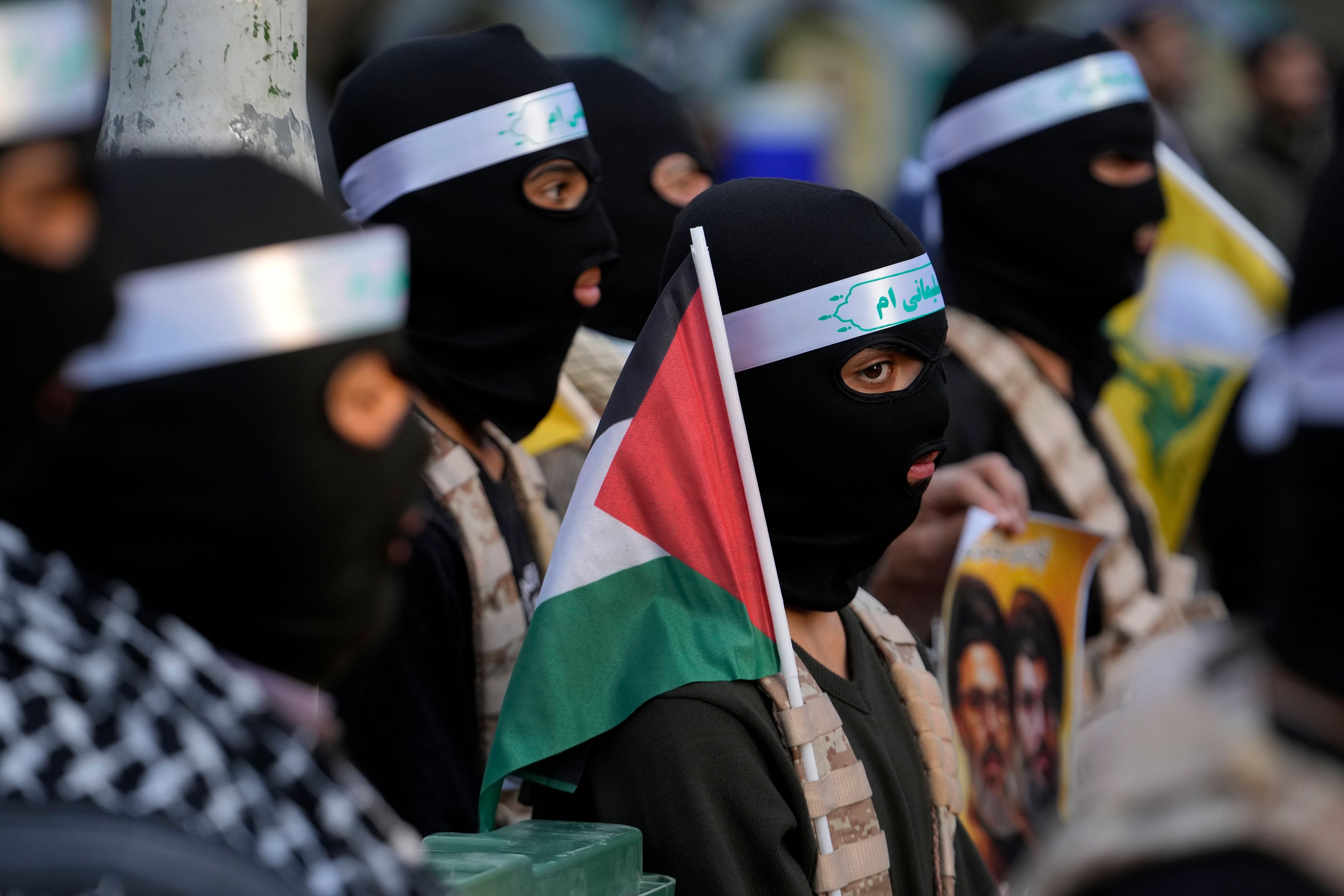 A group of the Iranian demonstrators cover their faces in the Palestinian and Lebanese militants style as one of them holds a Palestinian flag in a ceremony commemorating the late Hamas leader Yahya Sinwar and Hashem Safieddine, a powerful cleric who was expected to succeed slain Hezbollah leader Hassan Nasrallah and was killed by an Israeli airstrike in Beirut, at the Felestin (Palestine) Sq. in Tehran, Iran, Thursday, Oct. 24, 2024. (AP Photo/Vahid Salemi)