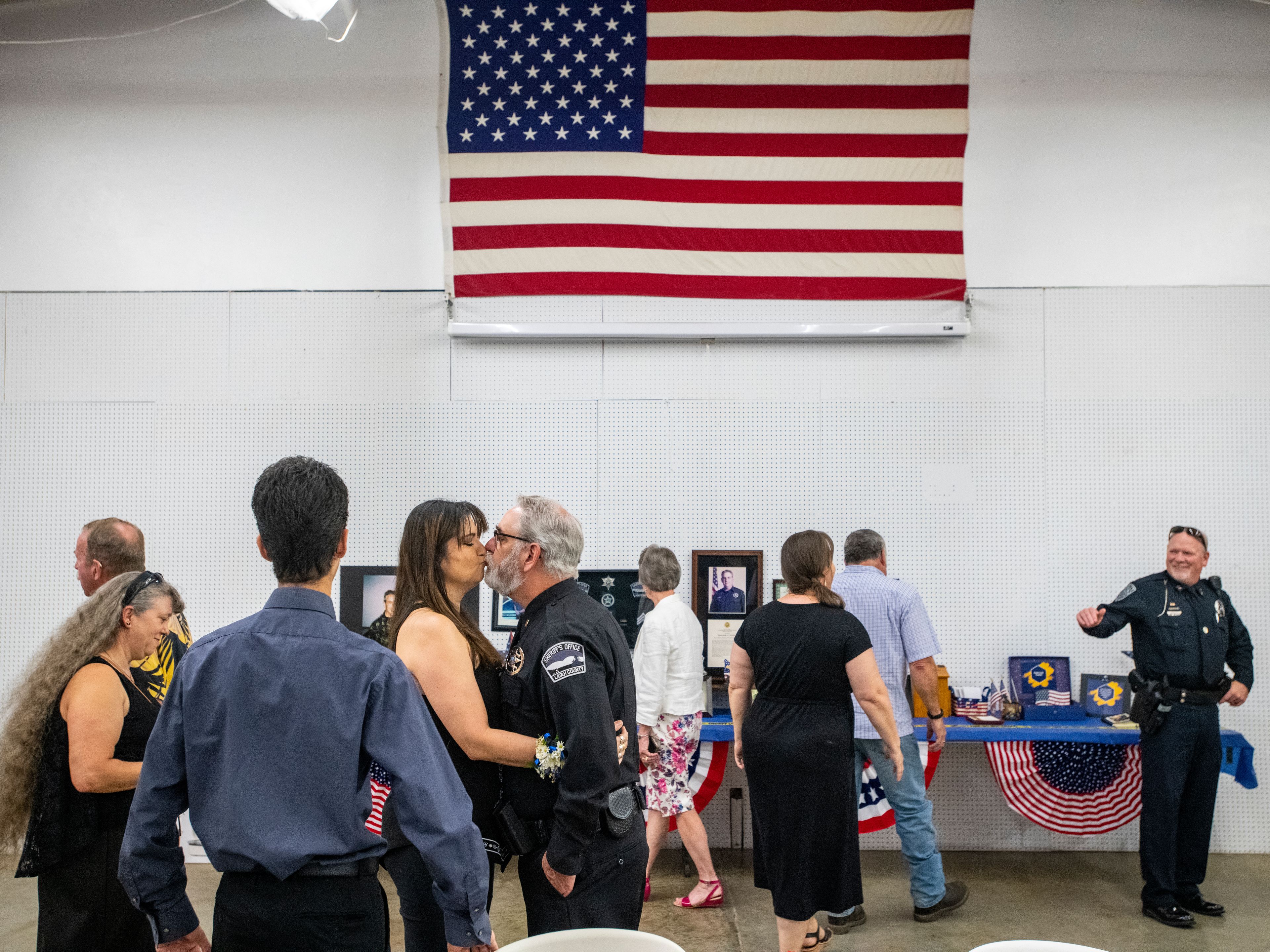 Lt. Brannon Jordan kisses his wife, Belen, underneath an American flag during Jordan’s retirement party Thursday at the Latah County Fair Office in Moscow.