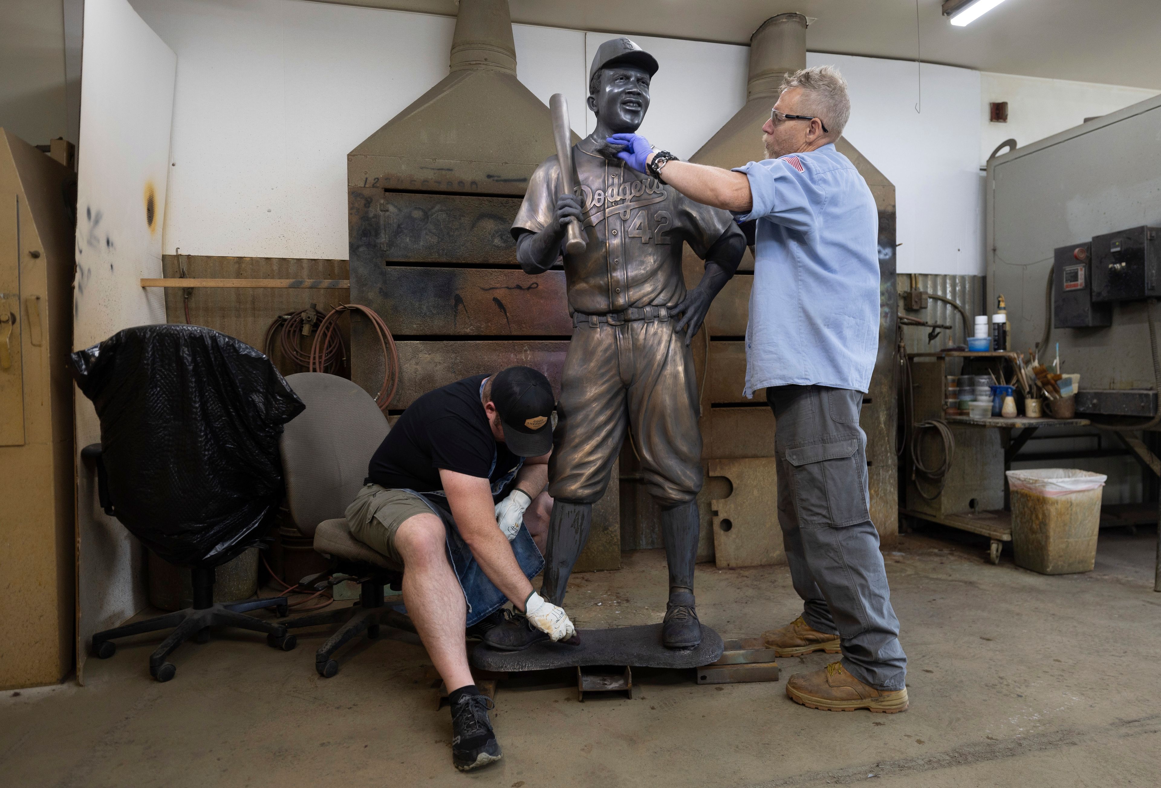 Nate Ford, left, and Jeff Herndon apply finishing touches to a statue of baseball hall-of-famer and civil rights pioneer Jackie Robinson in Loveland, Colo., on Wednesday, July 24, 2024. (Travis Heying/The Wichita Eagle via AP)