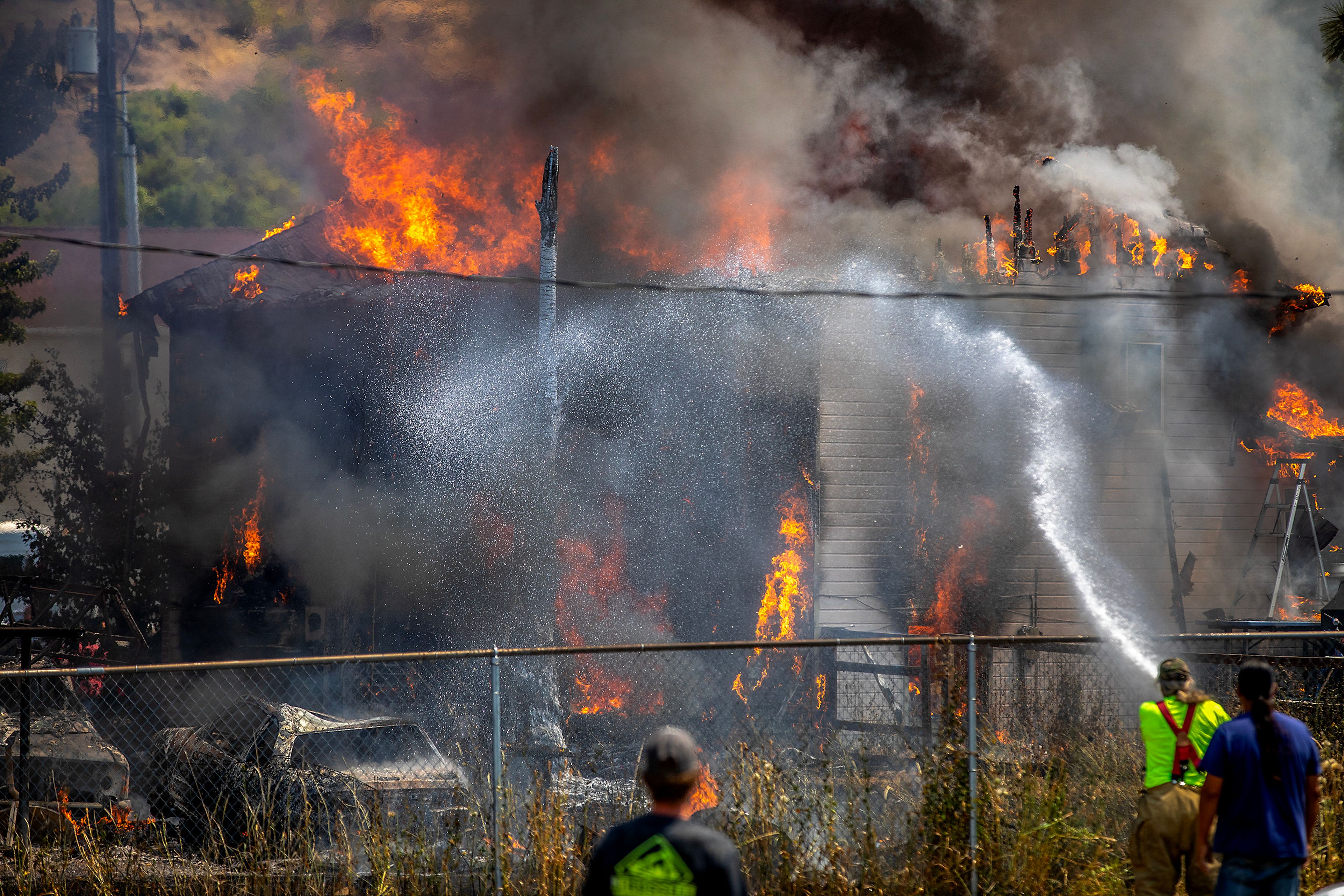 Firefighters spray down a burning home at the scene of structure fire Friday on Lolo Street in Lapwai. Two structures burned in the blaze.