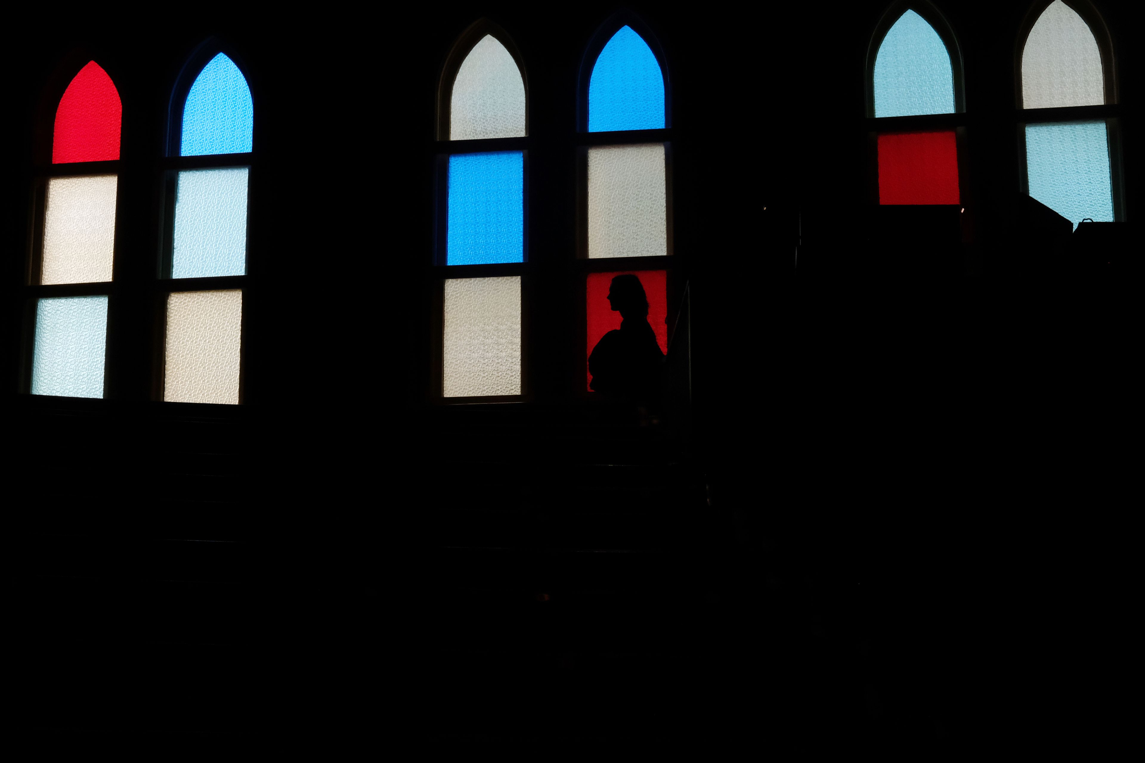 A woman is silhouetted against the stained-glass windows at the Ryman Auditorium, known as the Mother Church of Country music, in Nashville, Tenn., on July 30, 2024.