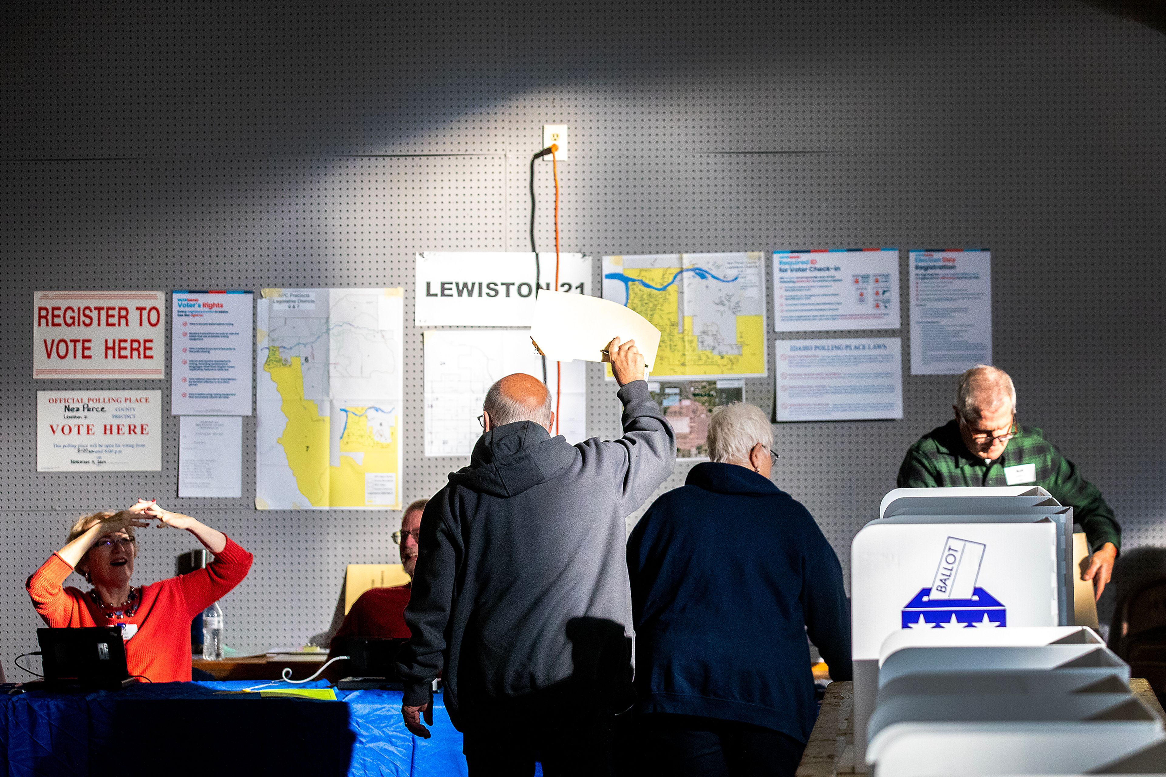 A voter holds their completed ballot up to give the poll worker a little shade from the direct sunlight streaming through the windows Tuesday at the Nez Perce County Fairgrounds in Lewiston.