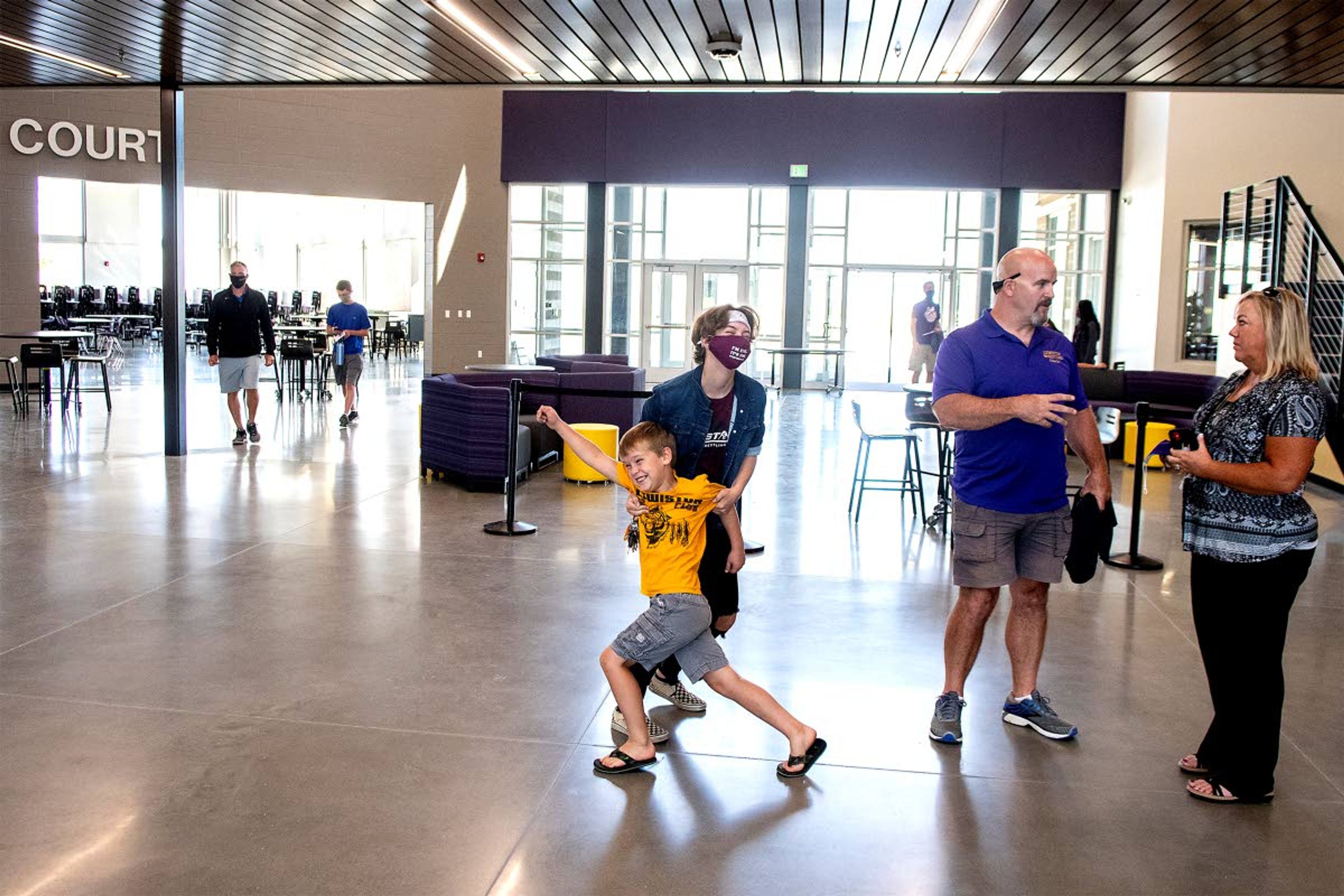 Maxx Johnson, 7, messes around with his sister, Kylee Johnson, 16, in the main commons of the new Lewiston High School as people tour the building on Friday.