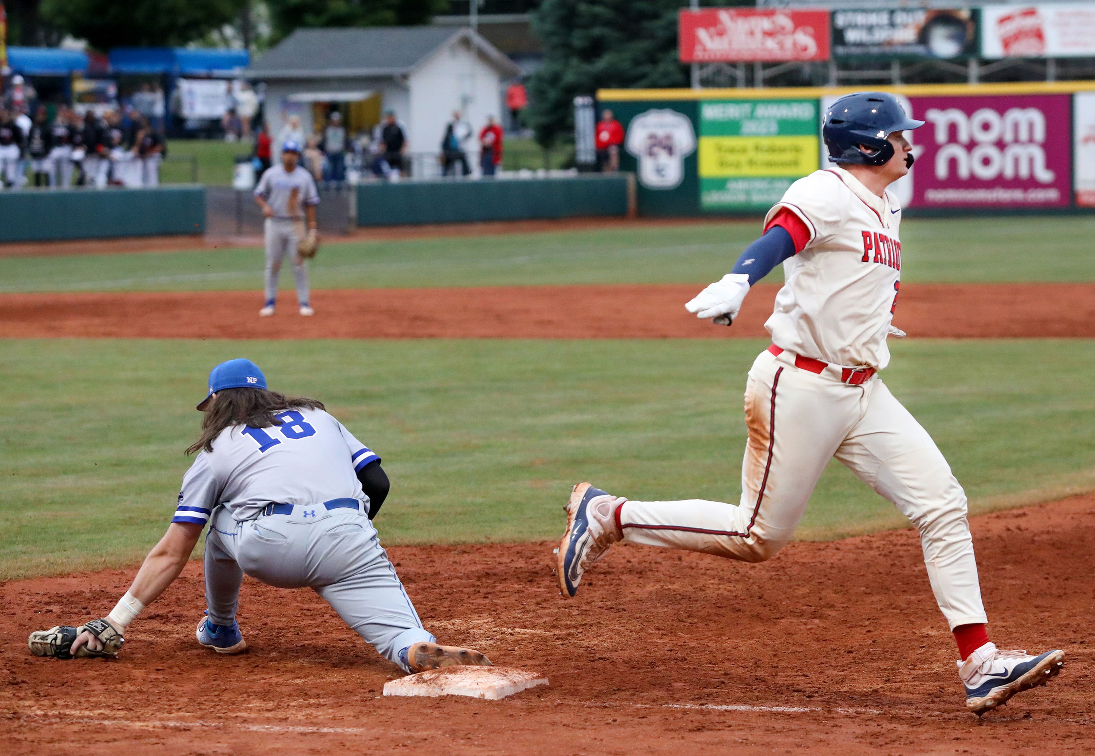 The Cumberlands’ Max Harper opens his arms to motion “safe” while running through first base as Tennessee Wesleyan first baseman Evan Magill kneels for a catch on the opening day of the NAIA World Series at Harris Field in Lewiston on Friday.