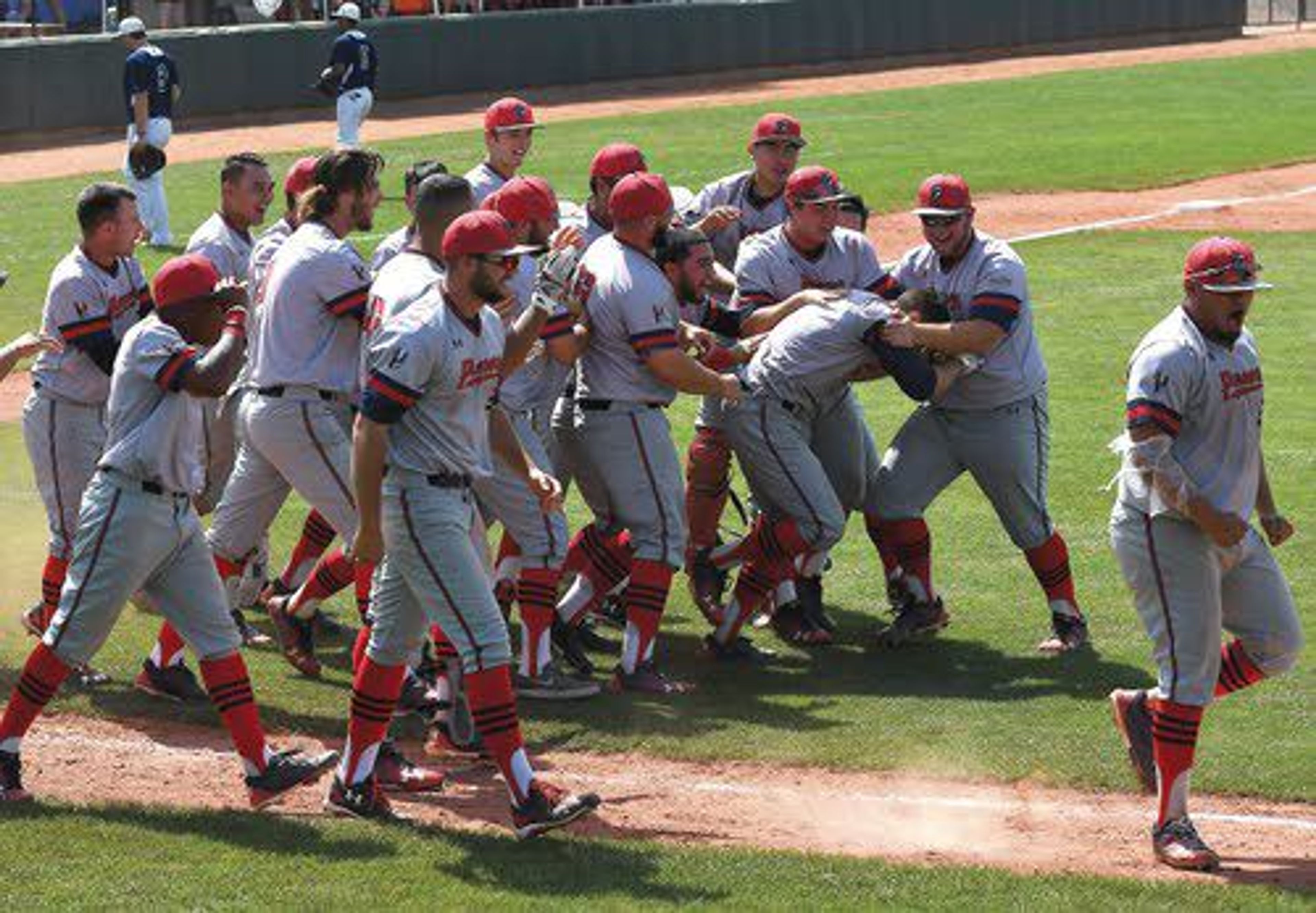 Antelope Valley players mob Tyler Pittmon after he smashed a walk-off home run in the bottom of the ninth inning. That gave the Pioneers a 2-1 victory over Reinhardt in Game 1 of the NAIA World Series on Friday morning at Harris Field. ABOVE RIGHT: AV starter Jacob Castillo fires an offering.