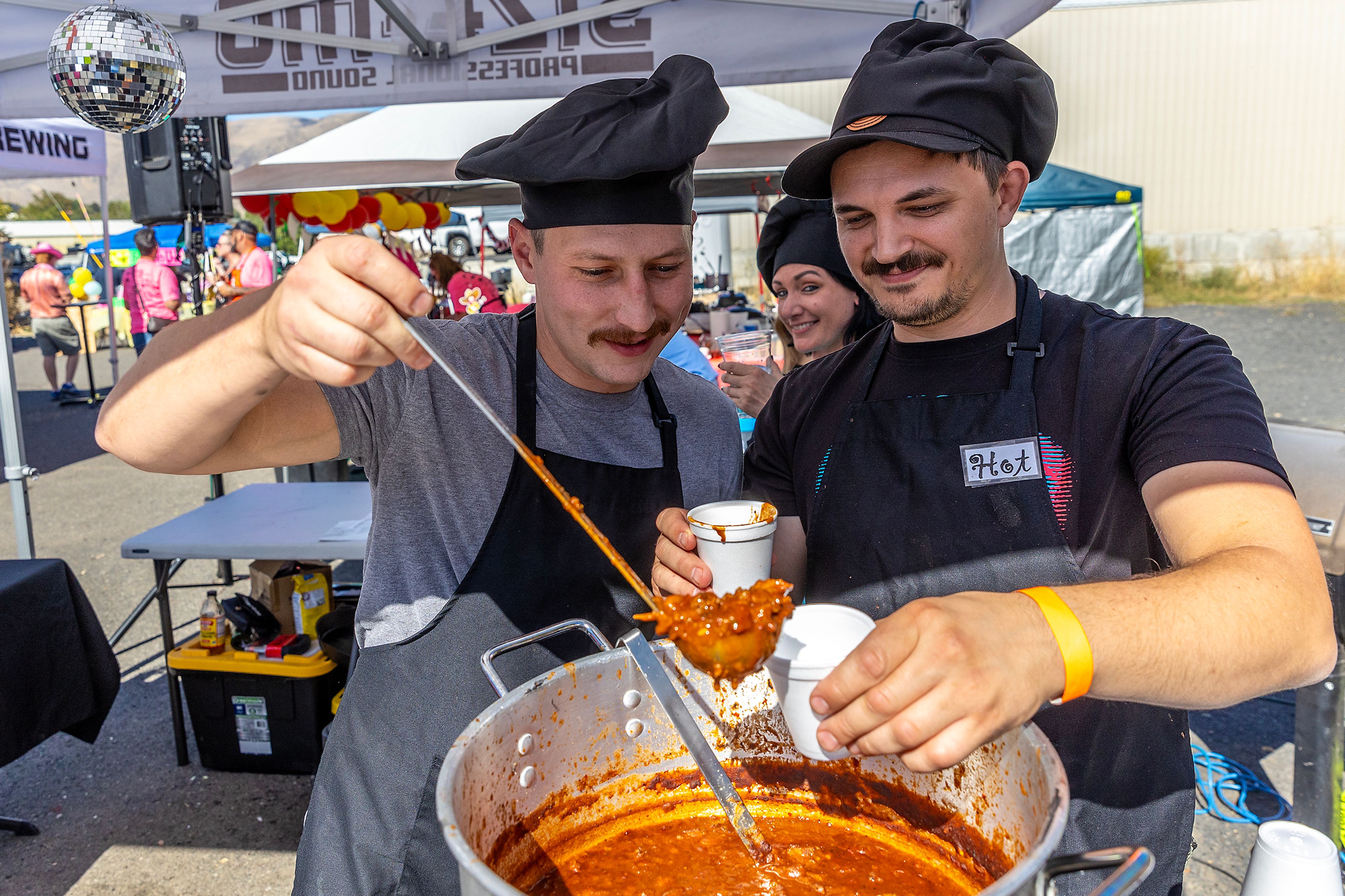 Dylan Villopoto, left, and Daro Frostad, fill up cups with chili as Misty Hinkley, looks on behind them during the 16th annual Idaho Fusion Chili Cookoff Saturday at Groundworks Brewing in Lewiston. The event featured 10 teams cooking chili and raised money for Idaho Fusion Dance Teams Dantz Dynamix. ,