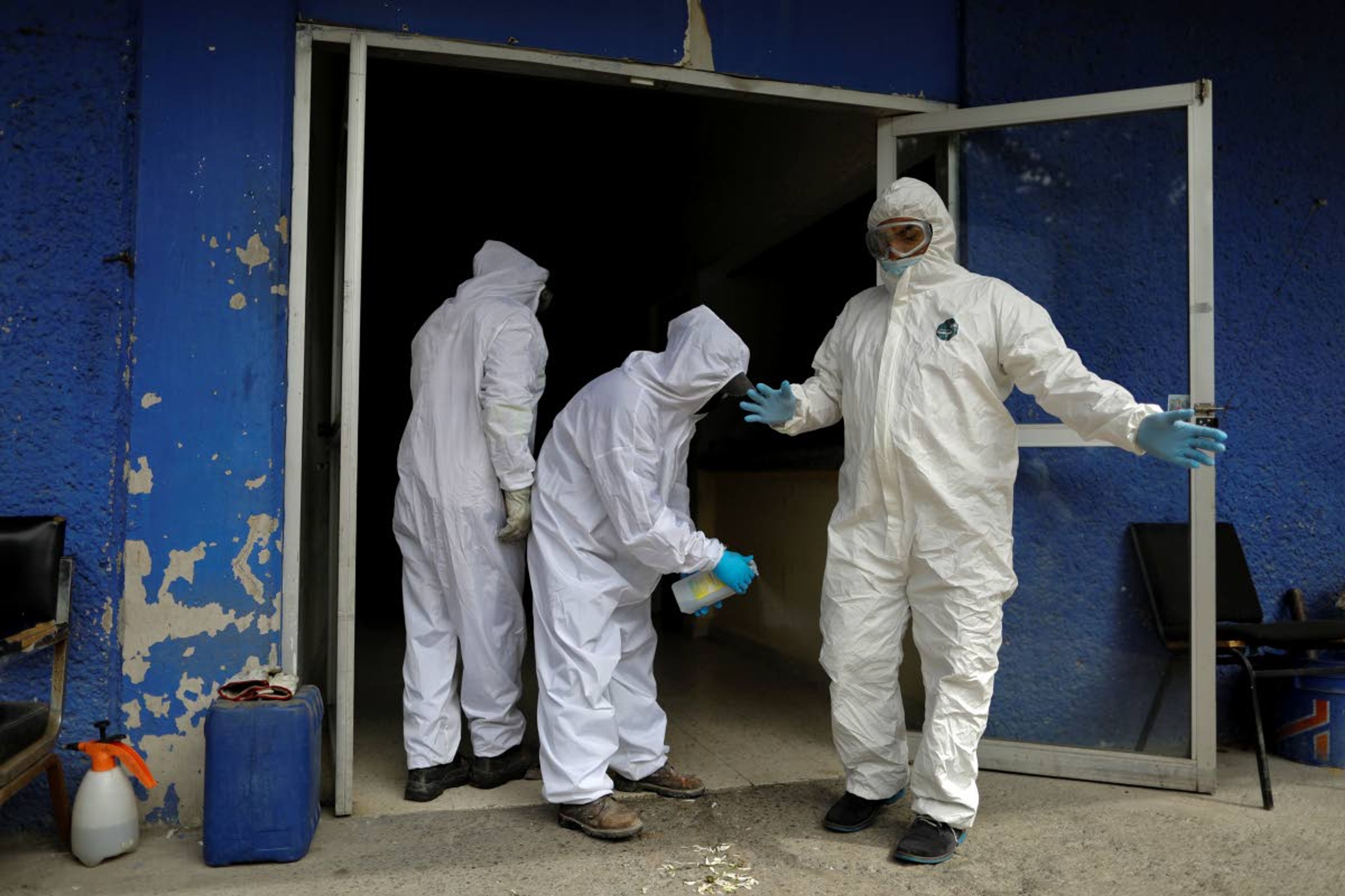 Workers spray each other with disinfectant solution after unloading the body of a person who died from suspected COVID-19, at the crematorium at Xilotepec Cemetery in Xochimilco, Mexico City, Monday, July 27, 2020. (AP Photo/Rebecca Blackwell)