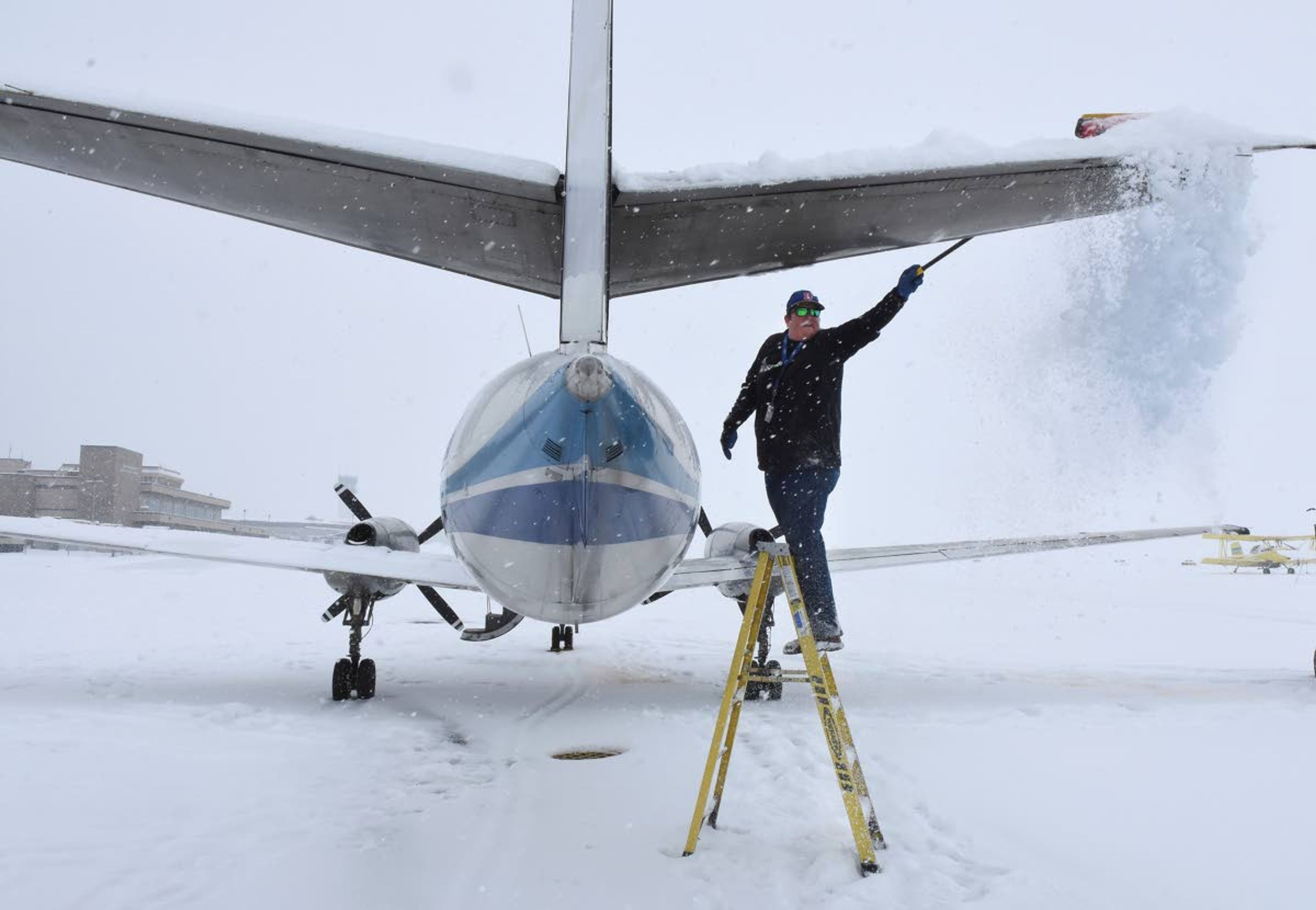 Ray Stout of Stout Flying Service brooms snow off an Ameriflight Metro cargo aircraft from Seattle before refueling and de-icing it. The airplane, which was loaded with packages, was diverted Wednesday morning from Pullman because of heavy winter conditions and was unloaded at the Lewiston-Nez Perce County Regional Airport instead. More snow is expected today throughout the region, though it may let up by the weekend.