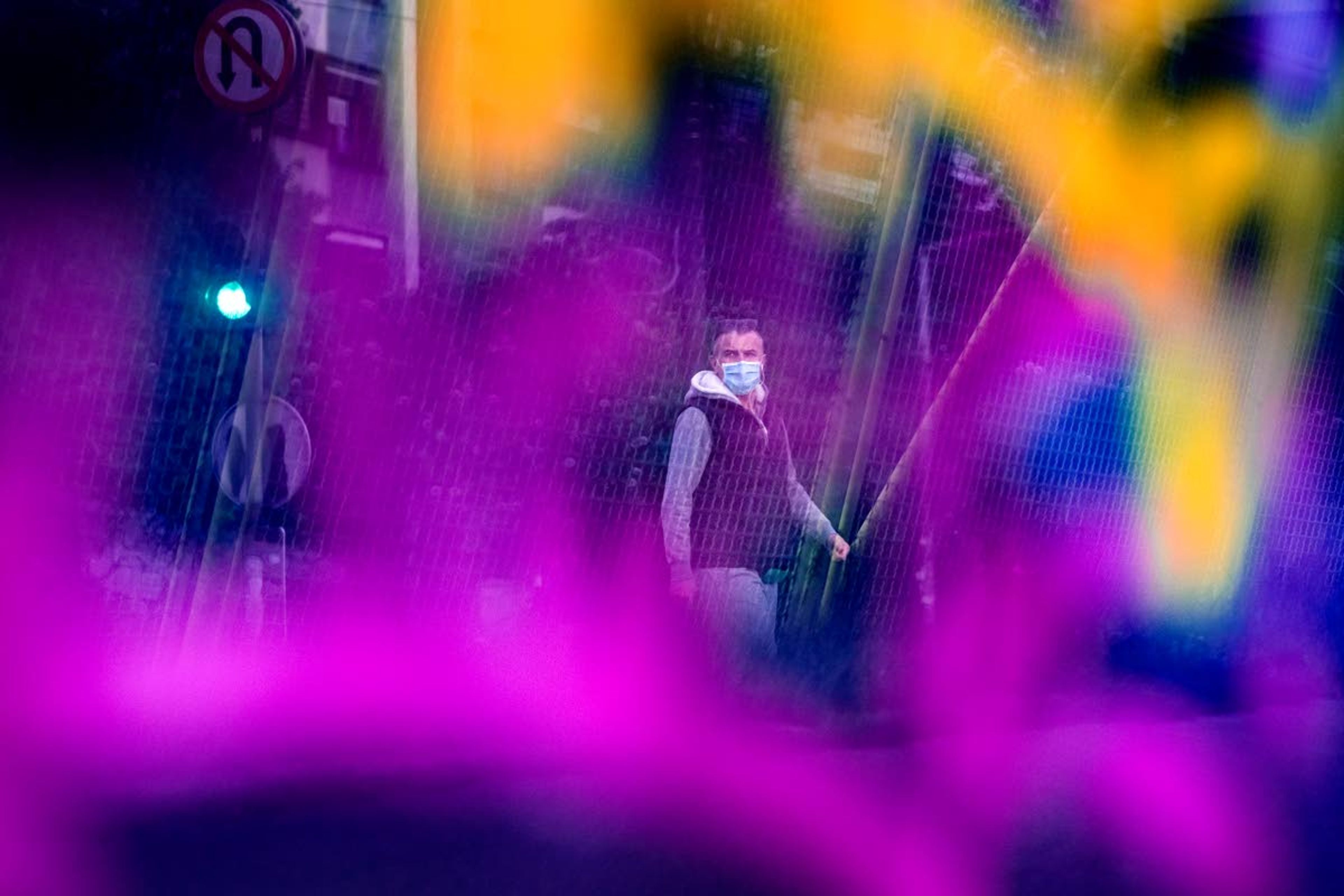 Seen through a bridge glass panel covered in graffiti a man wearing a face mask walks in Sarajevo, Bosnia, Wednesday, May 6, 2020. After nearly two months in lockdown, mosques in Bosnia have reopened to believers celebrating the islamic holy month of Ramadan, who can attend three daytime prayers as long as they observe social distancing rules and use protective equipment. (AP Photo/Kemal Softic)