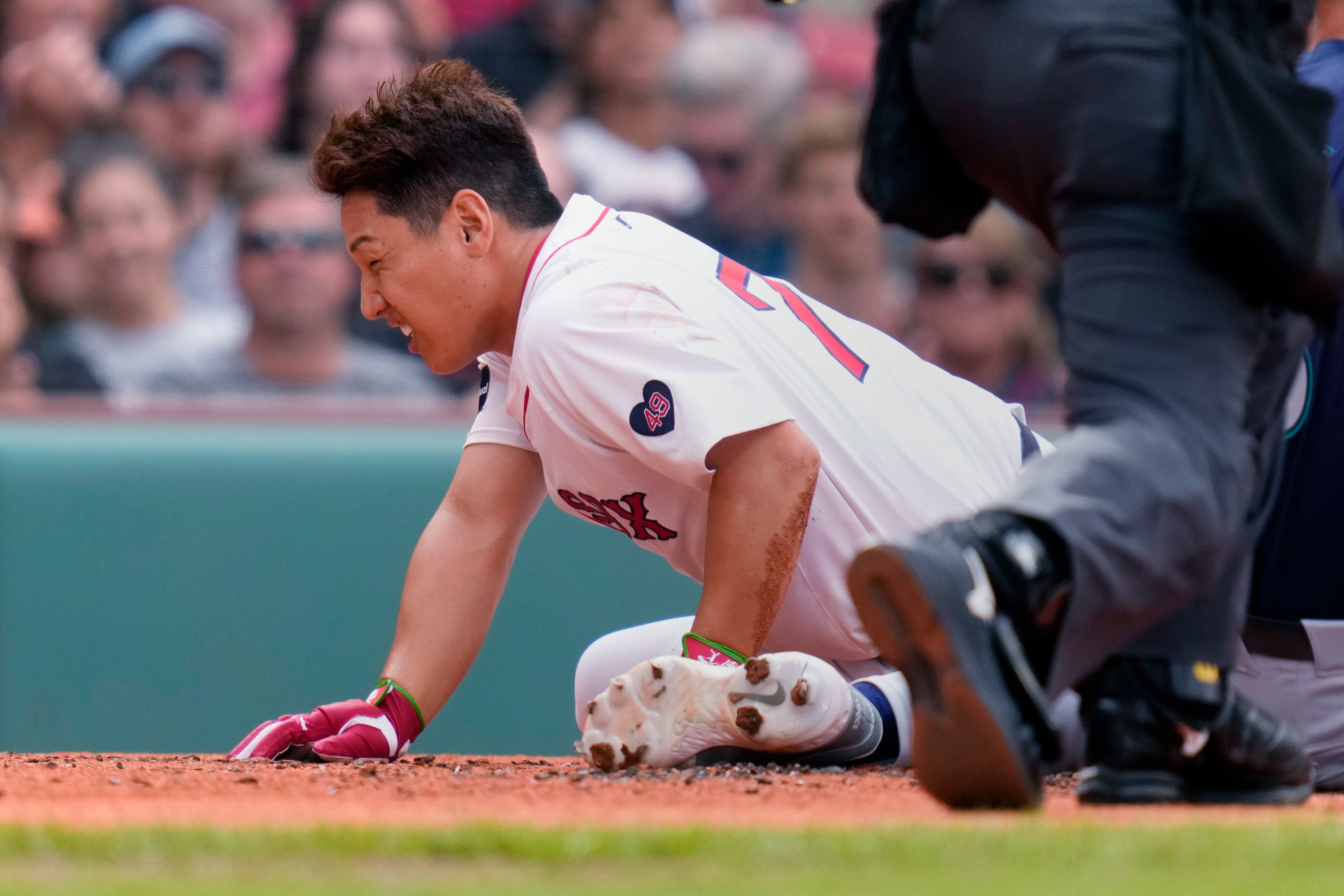 Boston Red Sox's Masataka Yoshida grimaces after colliding with Seattle Mariners pitcher George Kirby, not pictured, while scoring on a wild pitch during the first inning of a baseball game, Wednesday, July 31, 2024, in Boston. (AP Photo/Charles Krupa)