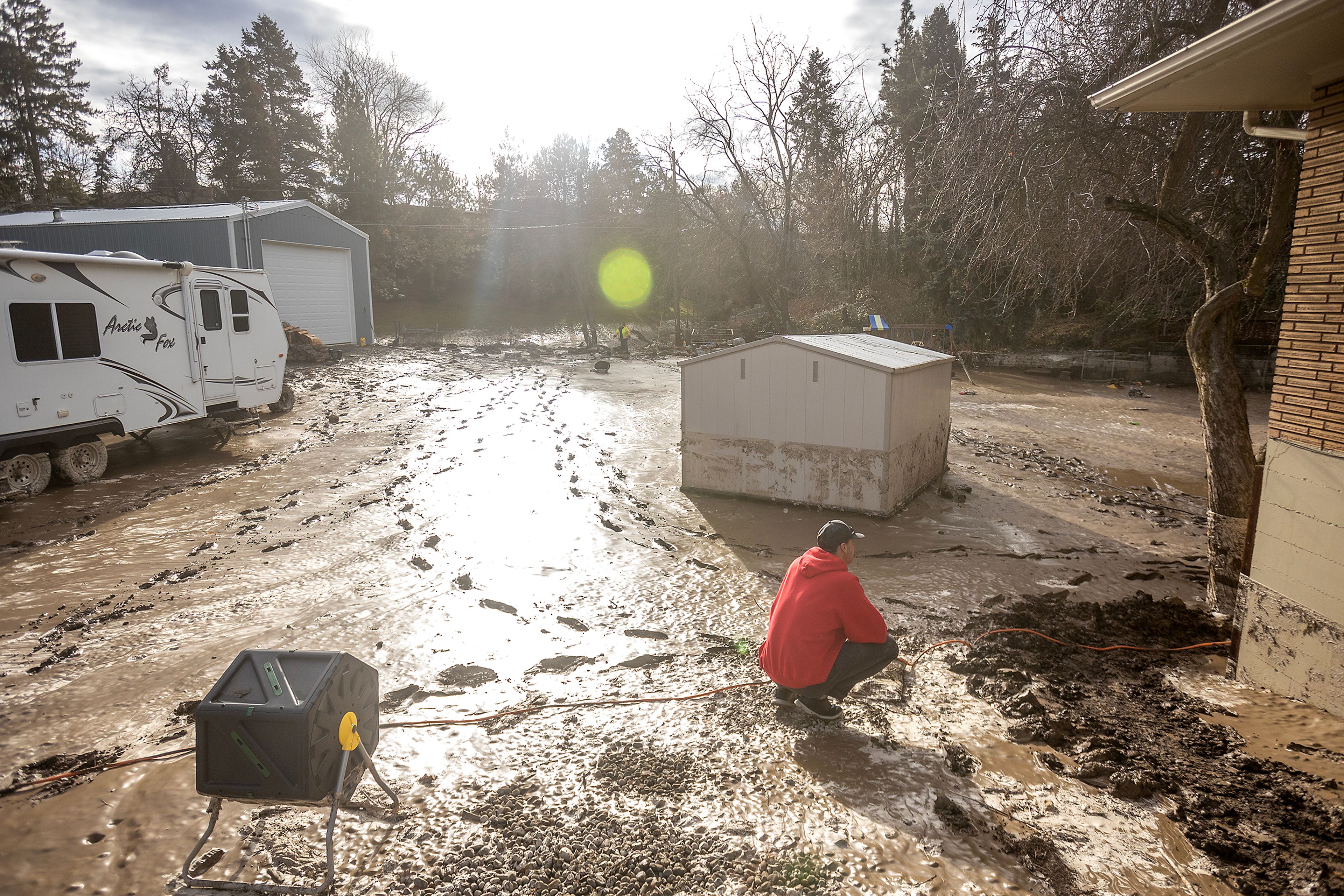 Ramone Royce looks over his mud and debris covered back yard after a water reservoir at the corner of 16th Avenue and 29th Street burst in the early hours of Wednesday morning in Lewiston.