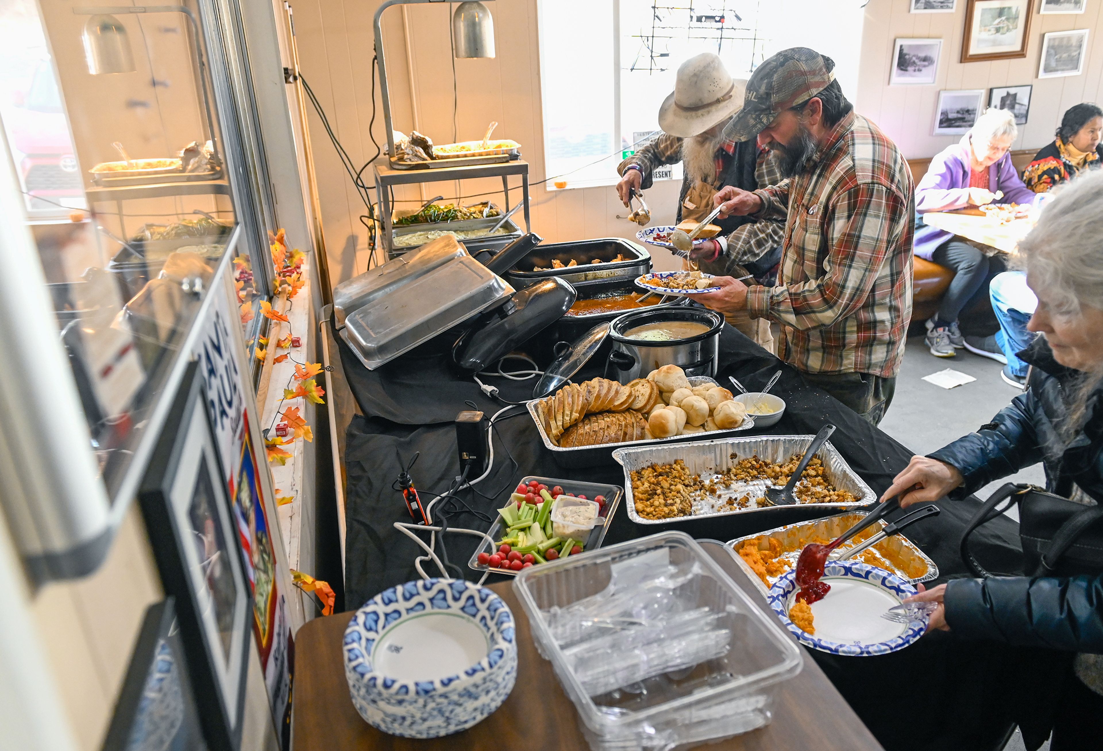 John Benn, left, and George “Crazy Bear” Schramm, center, both from Mount Idaho, serve up plates of food Thursday at Waha Grill’s annual free Thanksgiving meal on the outskirts of Lewiston.