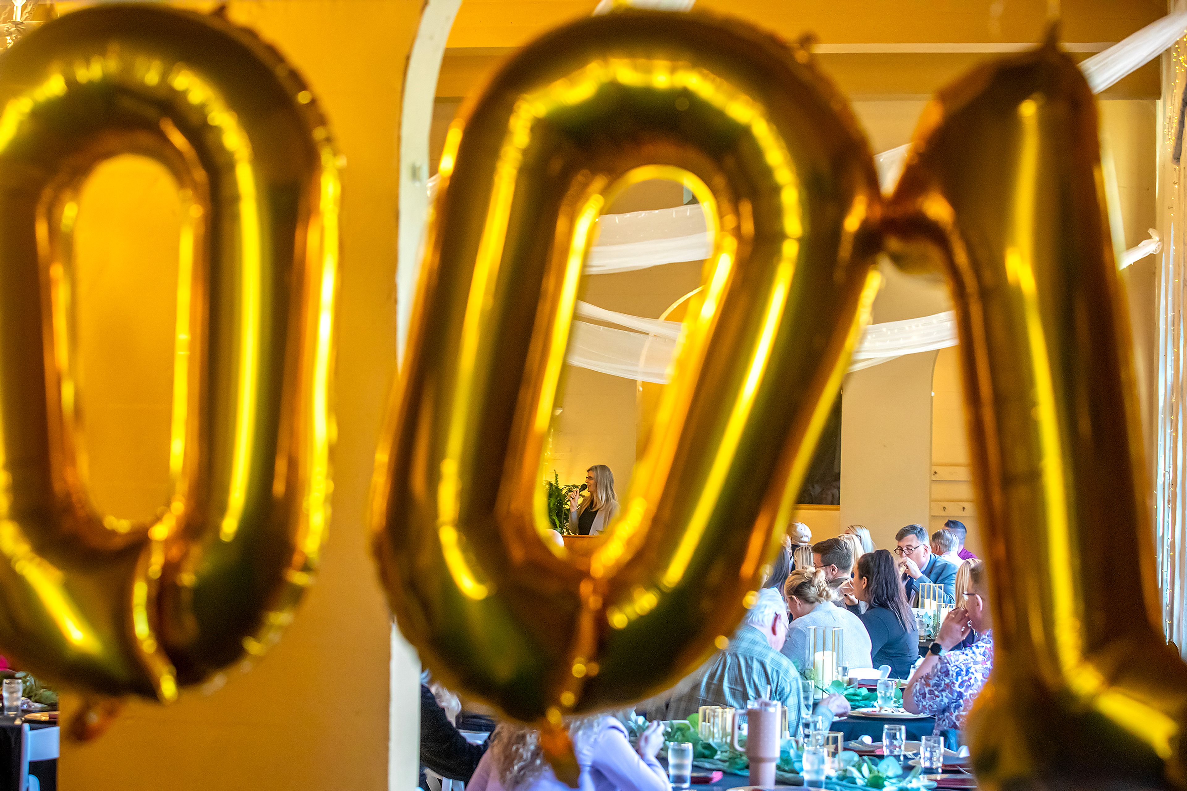 Linnea Noreen is seen through balloons spelling out "100" during a chamber of commerce event celebrates 100-year-old businesses Wednesday at the Lewis Clark Hotel in Lewiston.