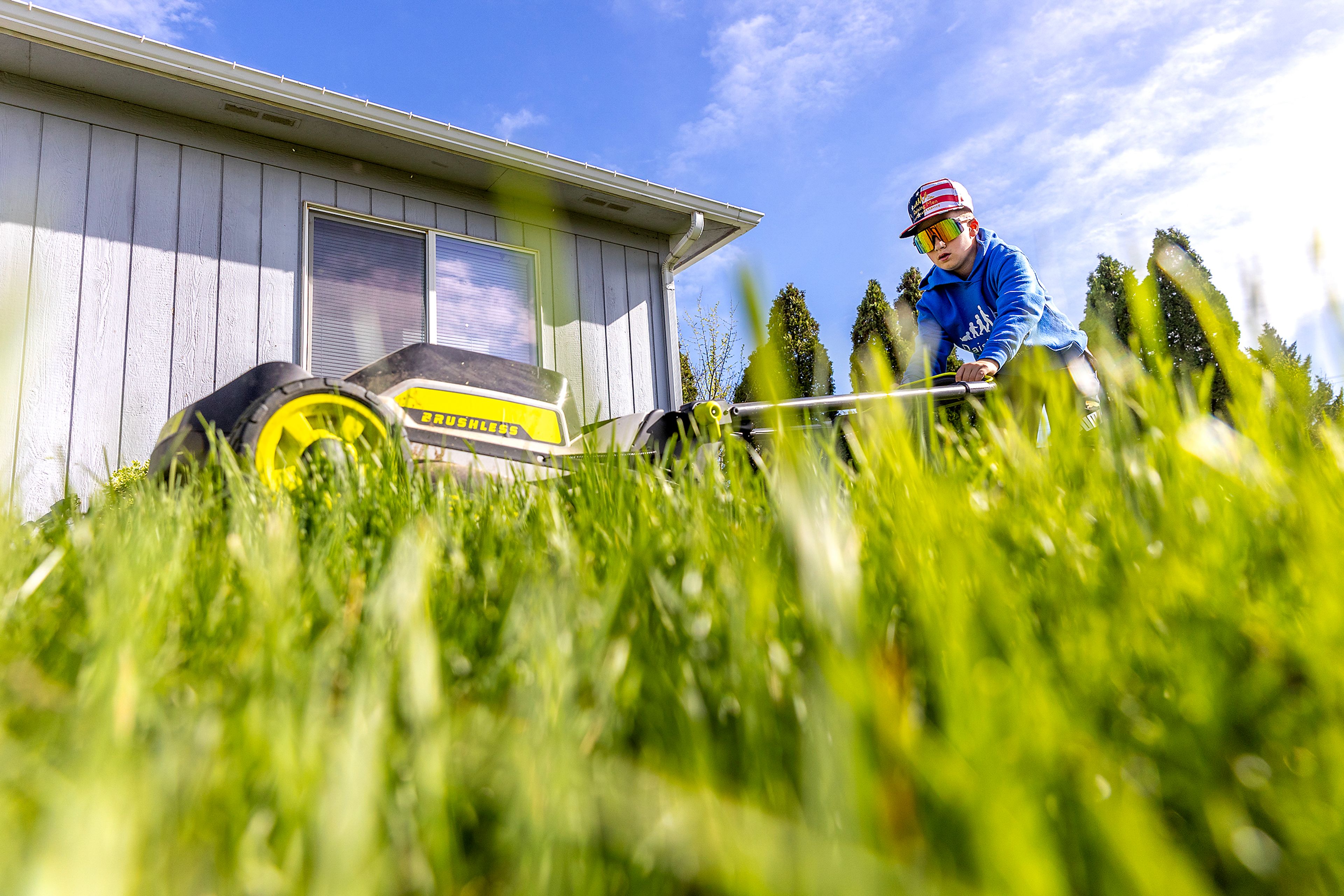 Kyler Frawley works on mowing a lawn Monday in Clarkston as part of the 50 yard challenge for elderly, veterans, disabled and people who can’t mow their own lawn.