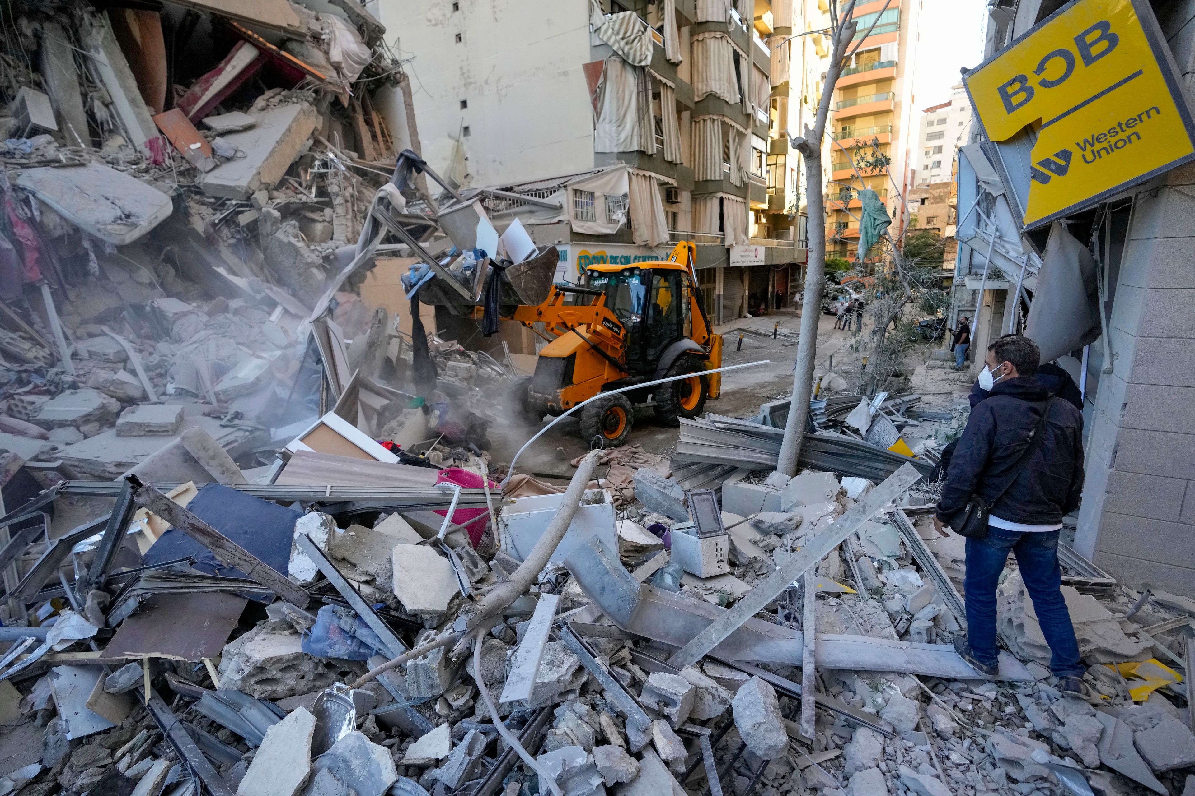 Rescue workers use a bulldozer to remove rubble of destroyed buildings at the site of an Israeli airstrike on Sunday night that hit several branches of the Hezbollah-run al-Qard al-Hassan in Beirut's southern suburb, Lebanon, Monday, Oct. 21, 2024. (AP Photo/Hassan Ammar)