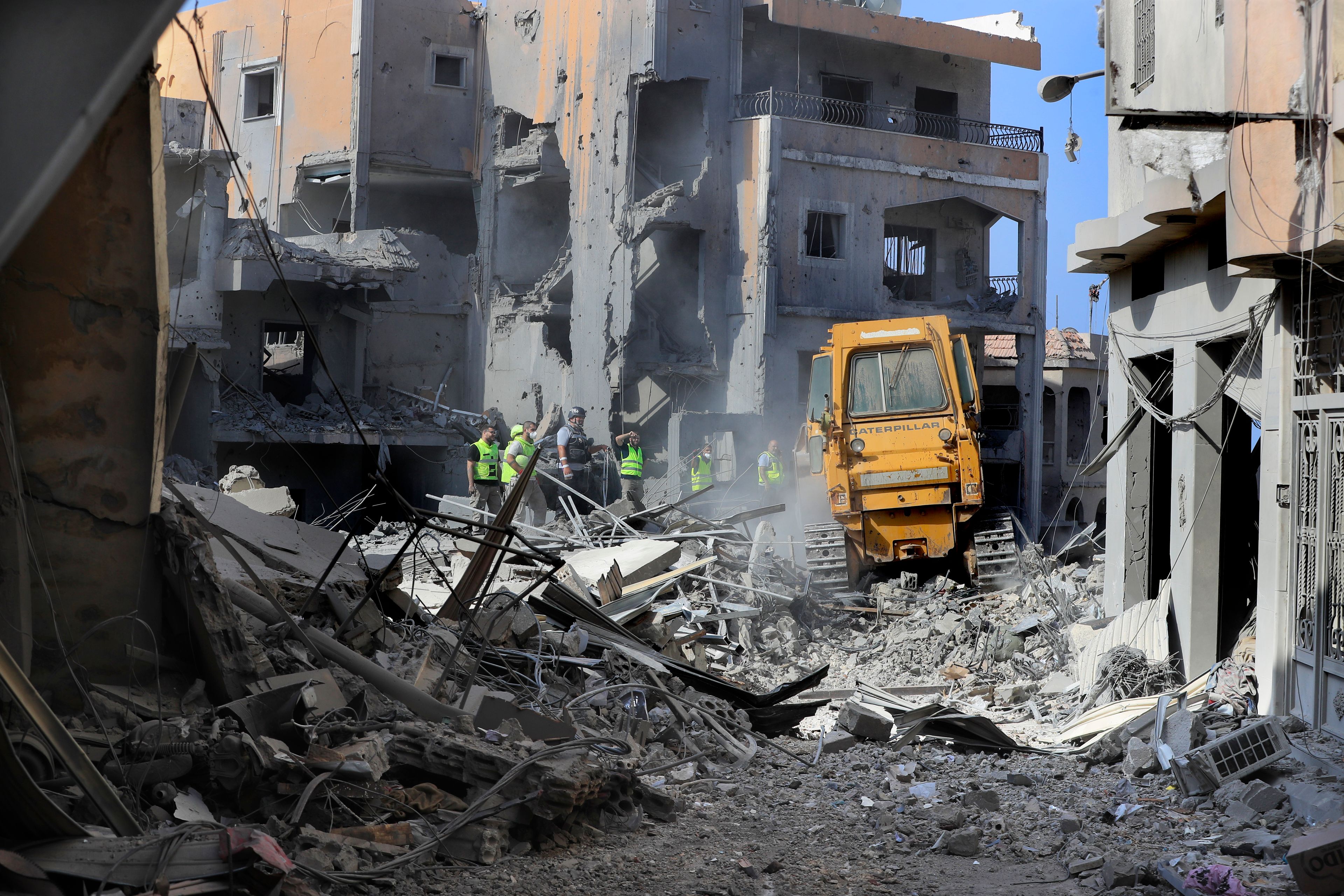 Rescue workers use a bulldozer to remove rubble of destroyed buildings, as they search for victims at the site that was hit by Israeli airstrikes in Qana village, south Lebanon, Wednesday, Oct. 16, 2024. (AP Photo/Mohammed Zaatari)