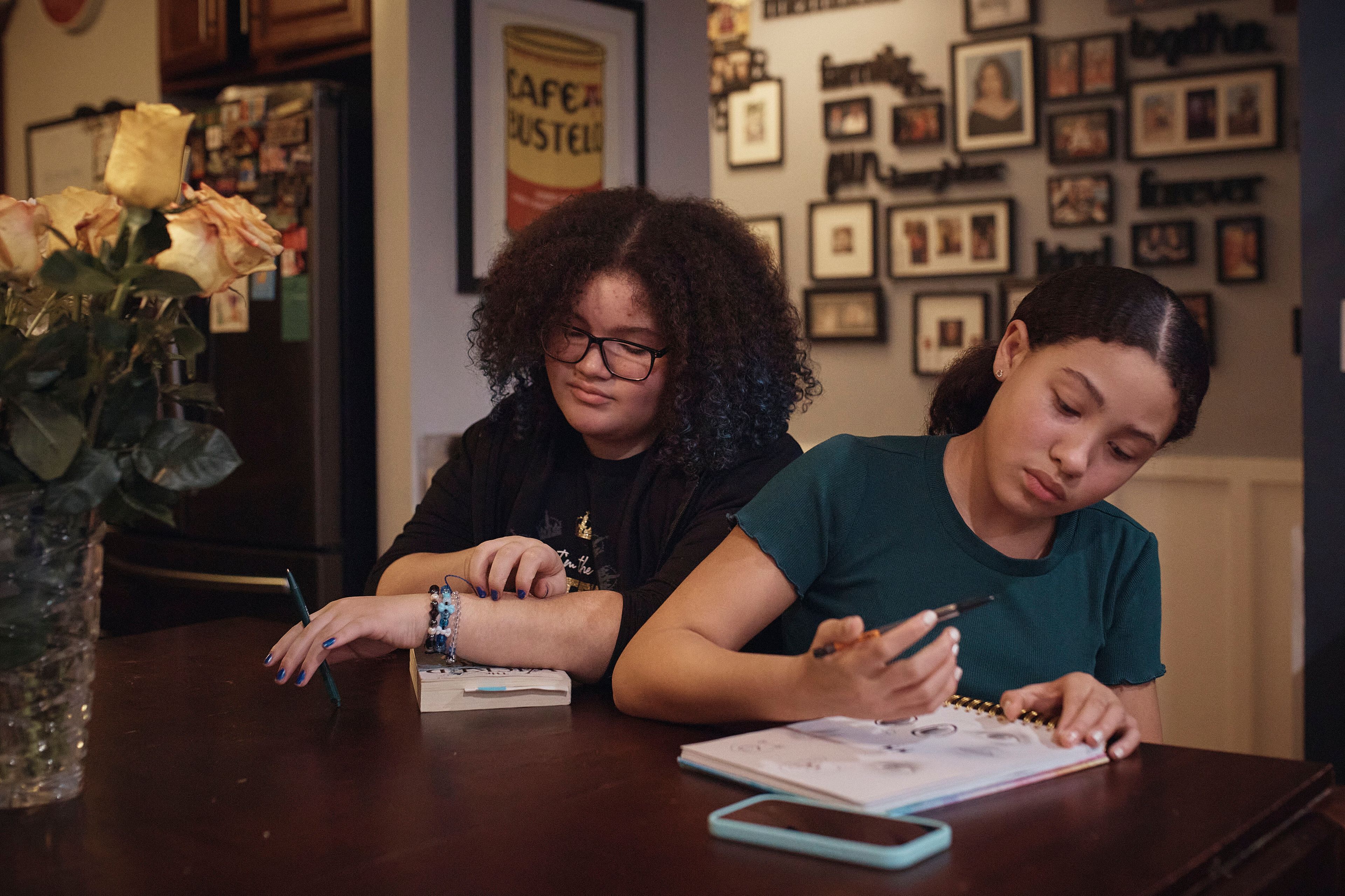 Gionna Durham, 13, left, spends time in the kitchen as her sister Grace Durham, 11, right, draws on Saturday, Jan. 27, 2024, in New York. It is hard to be a teenager today without social media. For those trying to stay off social platforms at a time when most of their peers are immersed, the path can be challenging, isolating and at times liberating. It can also be life-changing.