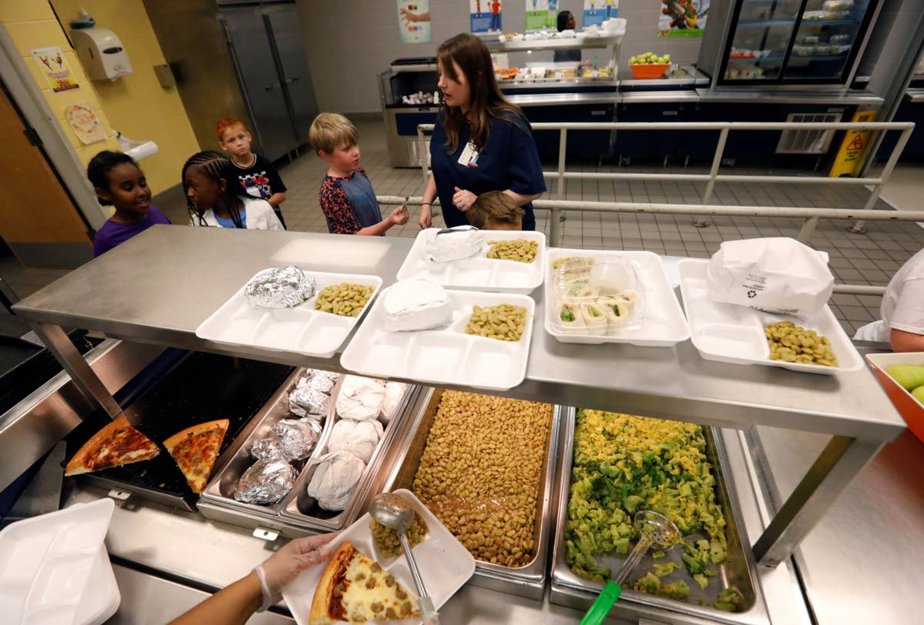 A teacher lines up the students for school-prepared lunches at Madison Crossing Elementary School in Canton, Miss., Friday, Aug. 9, 2019. Scott Clements, director of child nutrition at the Mississippi education department, said they've ordered two truckloads of trade mitigation pulled pork and four loads of kidney beans for use in their cafeterias. The products are coming from the U.S. Department of Agriculture, which is giving away the foods it’s buying to help farmers hurt by trade negotiations. (AP Photo/Rogelio V. Solis)