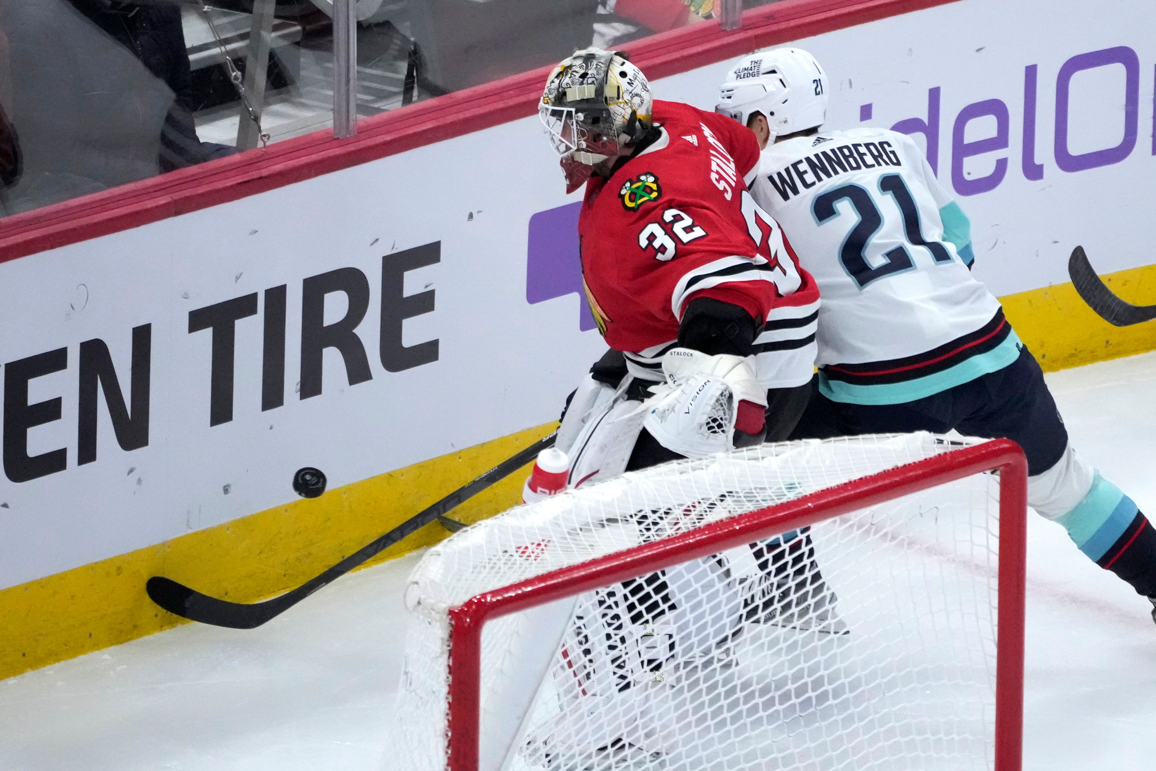 Chicago Blackhawks goaltender Alex Stalock (32) and Seattle Kraken's Alex Wennberg vie for the puck behind the net during the second period of an NHL hockey game Saturday, Jan. 14, 2023, in Chicago. (AP Photo/Charles Rex Arbogast)