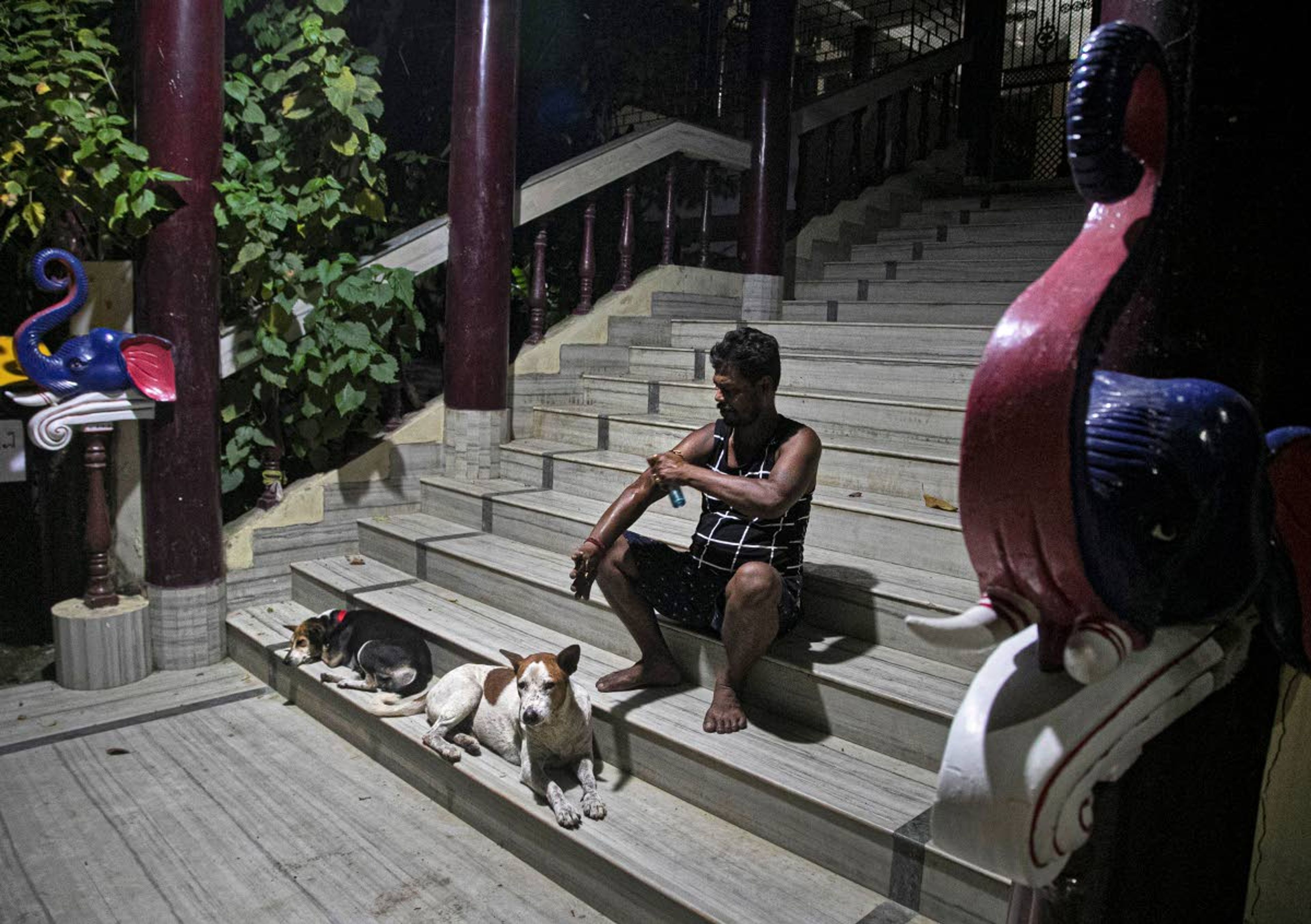 Ramananda Sarkar, 43, sanitizes his hands on the steps of a Goddess Kali temple after cremating bodies of COVID-19 victims in Gauhati, India, Tuesday, Sept. 15, 2020. While Hindu's believe cremation rights are sacred and release the dead person's soul from the cycle of rebirth, those who actually deal with corpses are looked down upon. It's a stigma that's only been made worse by the coronavirus, which has killed more than 100,000 people in India out of 6.4 million reported infections. Sarkar said he alone has cremated more than 450 COVID-19 victims. (AP Photo/Anupam Nath)