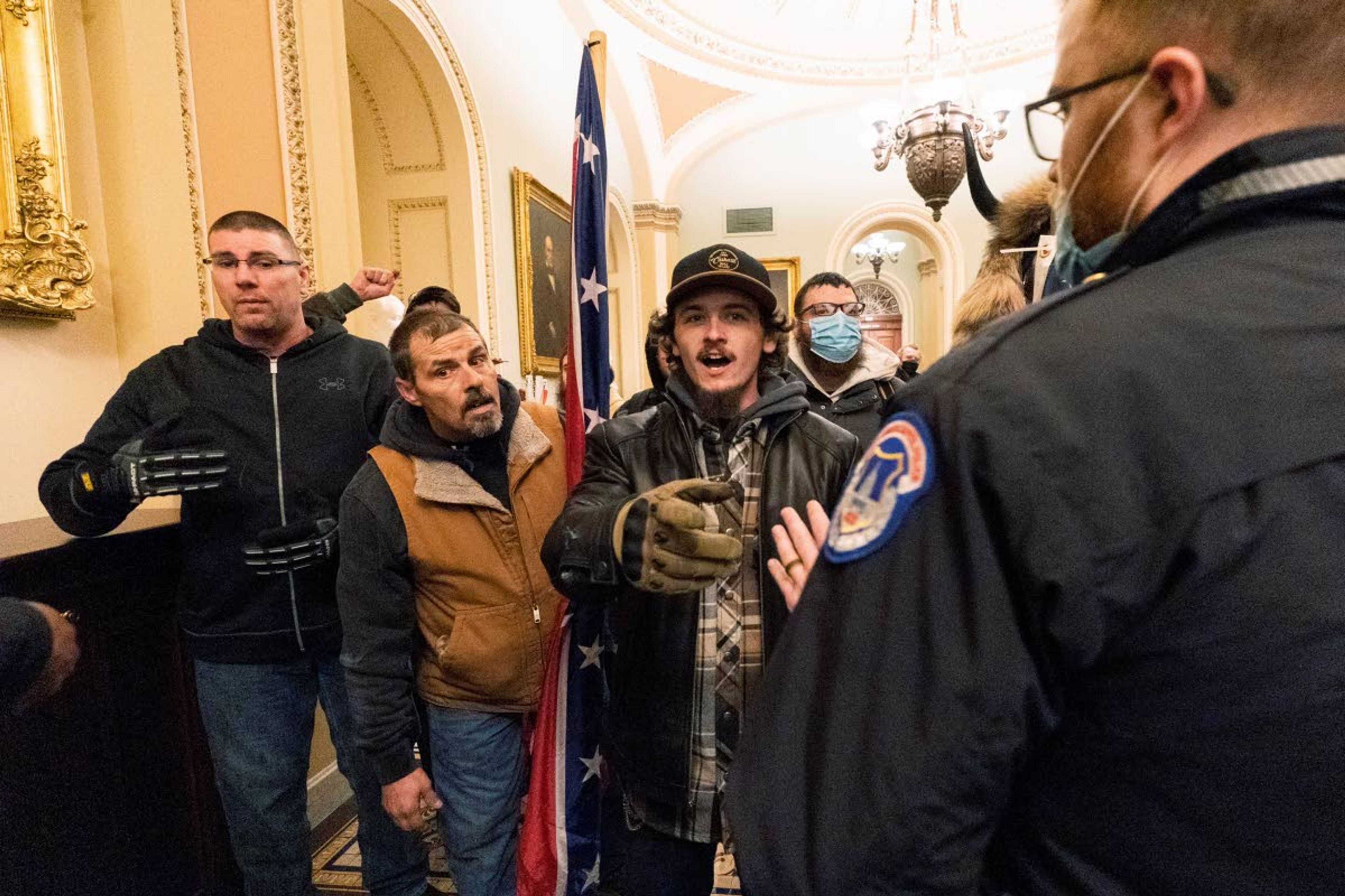 FILE - In this Wednesday, Jan. 6, 2021, file photo, Kevin Seefried, second from left, holds a Confederate battle flag as he and other insurrectionists loyal to President Donald Trump are confronted by U.S. Capitol Police officers outside the Senate Chamber inside the Capitol in Washington. War-like imagery began to take hold in Republican circles after the attack on the U.S. Capitol by a mob of Trump's supporters, with some elected officials and party leaders rejecting pleas to tone down rhetoric calling for a second civil war.(AP Photo/Manuel Balce Ceneta)