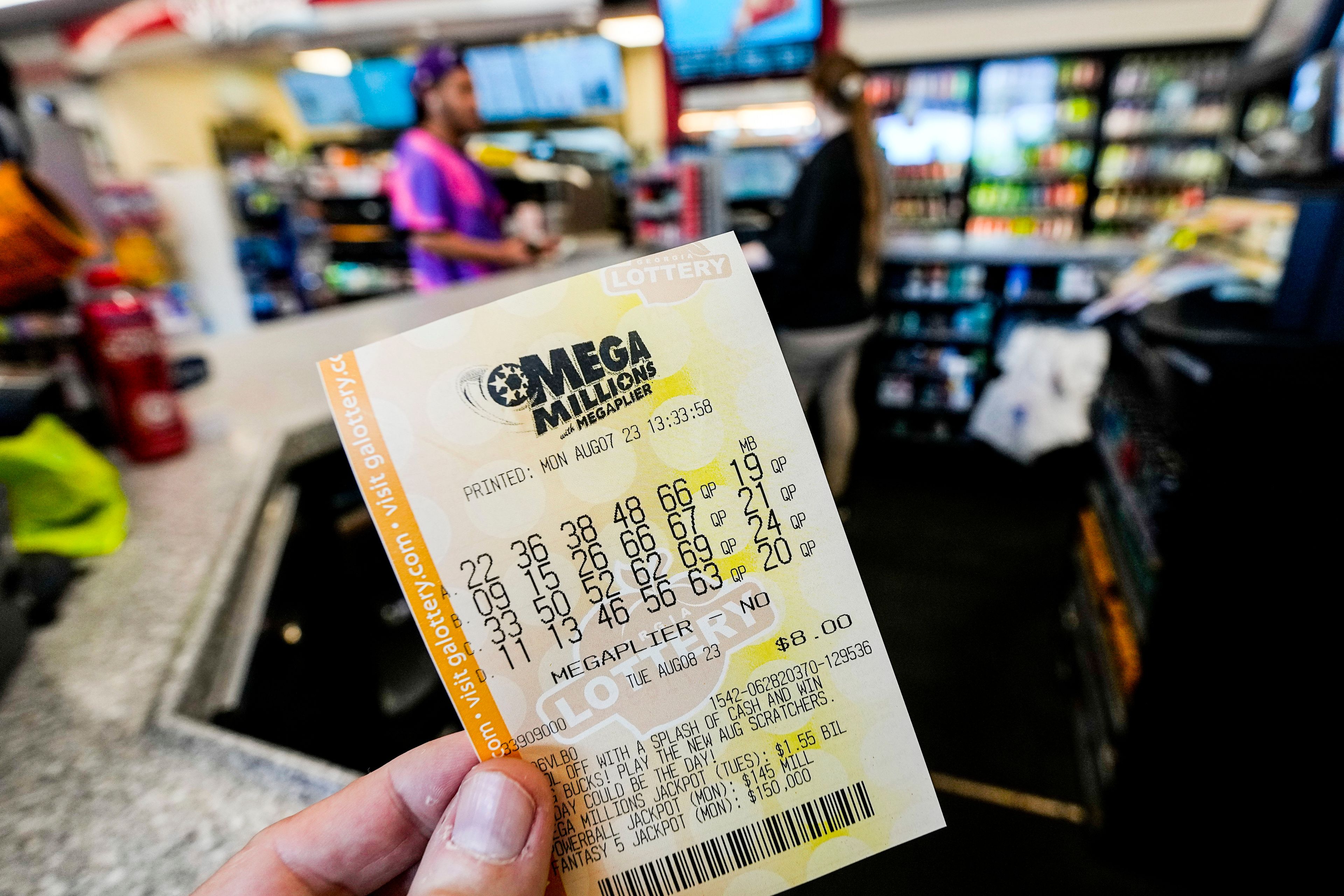 FILE - A Mega Millions ticket is seen as a person makes a purchase inside a convenience store, Aug. 7, 2023, in Kennesaw, Ga.