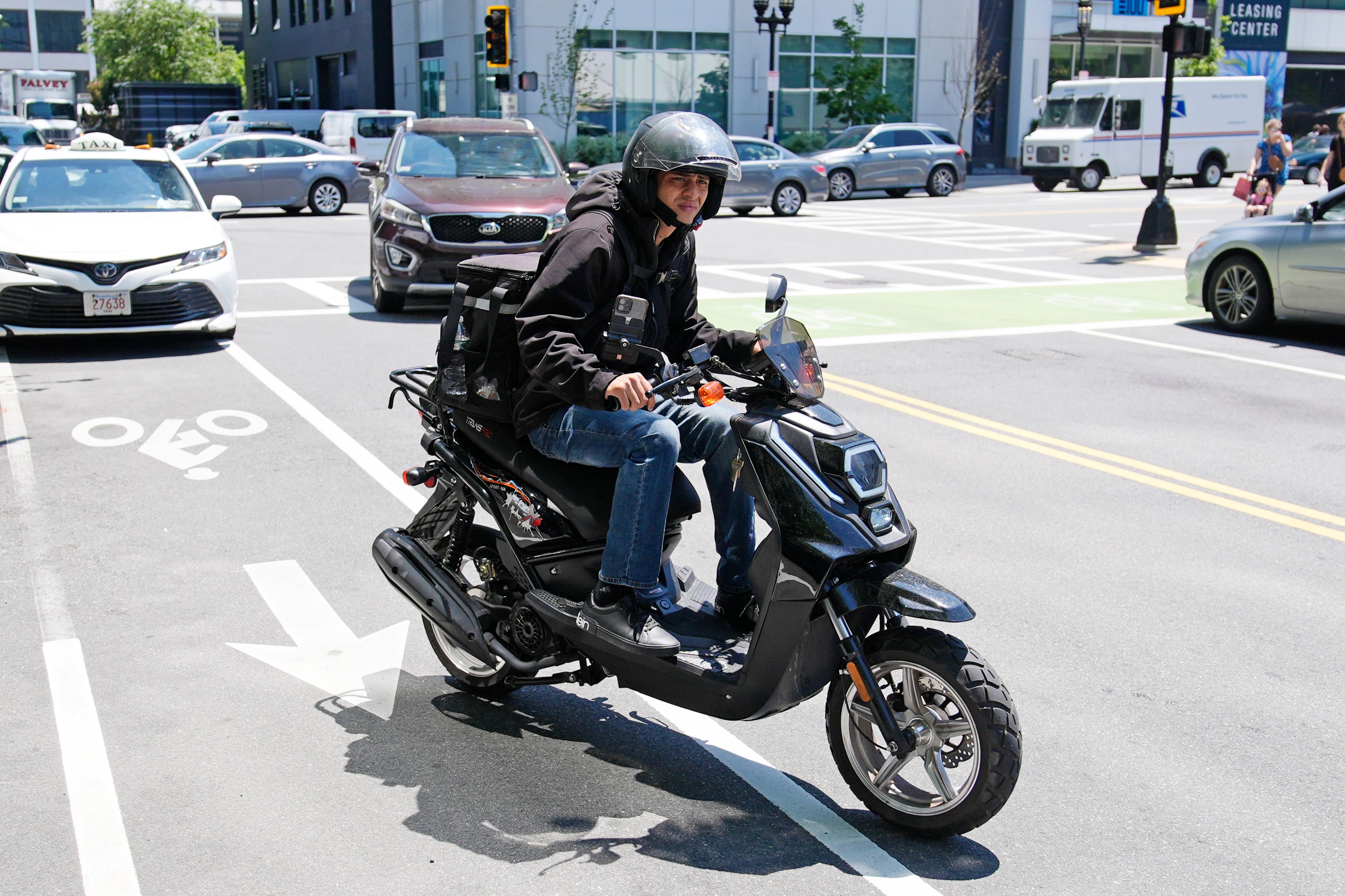 A delivery driver on a scooter heads out on a delivery in the Seaport District, Friday, June 7, 2024, in Boston. A soaring demand for food delivered fast has spawned small armies of couriers in a growing number of cities where delivery scooters, motorcycles and mopeds zip in and out of traffic and hop onto sidewalks alongside startled pedestrians racing to drop off salads and sandwiches.