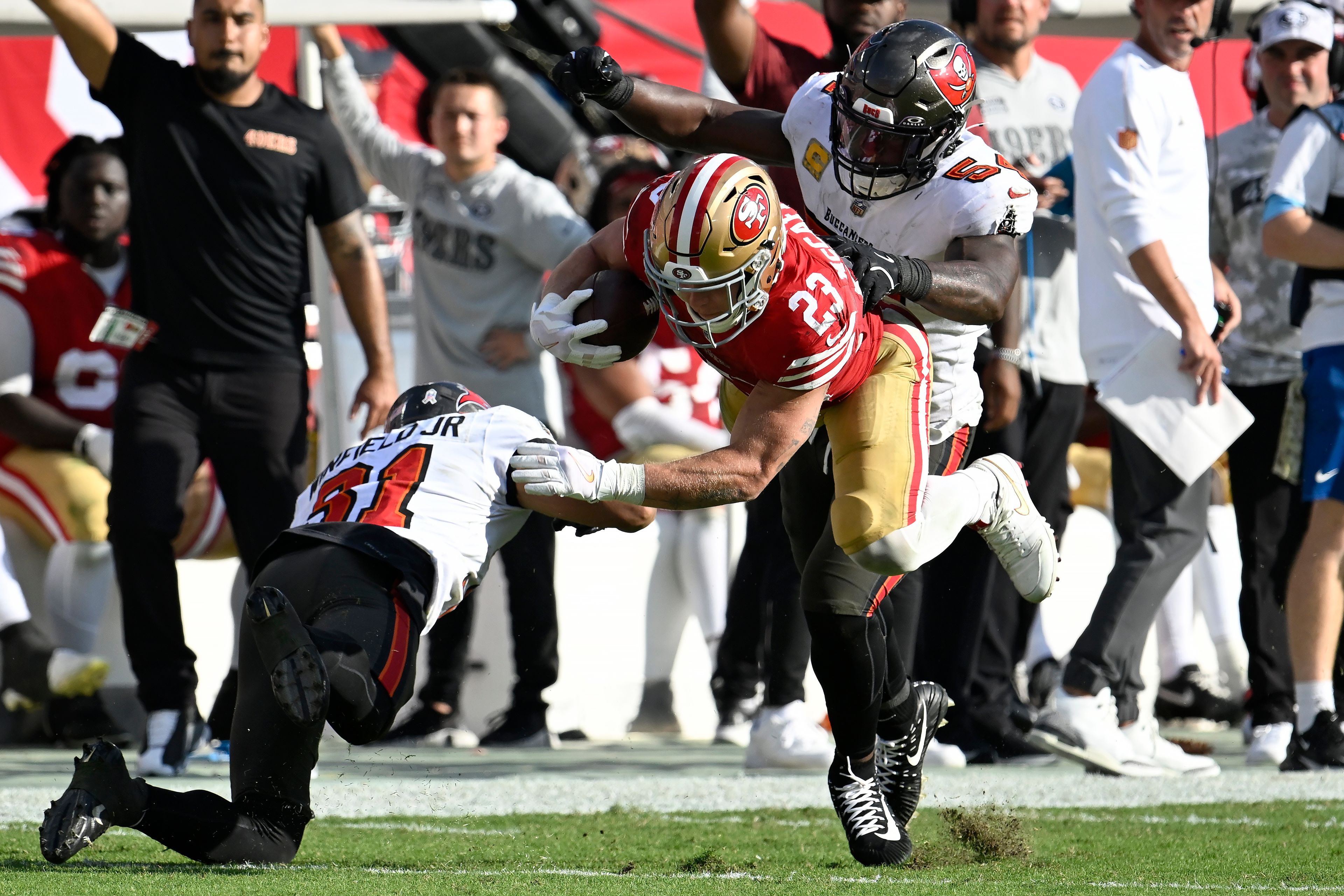 San Francisco 49ers running back Christian McCaffrey (23) runs against Tampa Bay Buccaneers safety Antoine Winfield Jr. (31) and linebacker Lavonte David during the second half of an NFL football game in Tampa, Fla., Sunday, Nov. 10, 2024. (AP Photo/Jason Behnken)