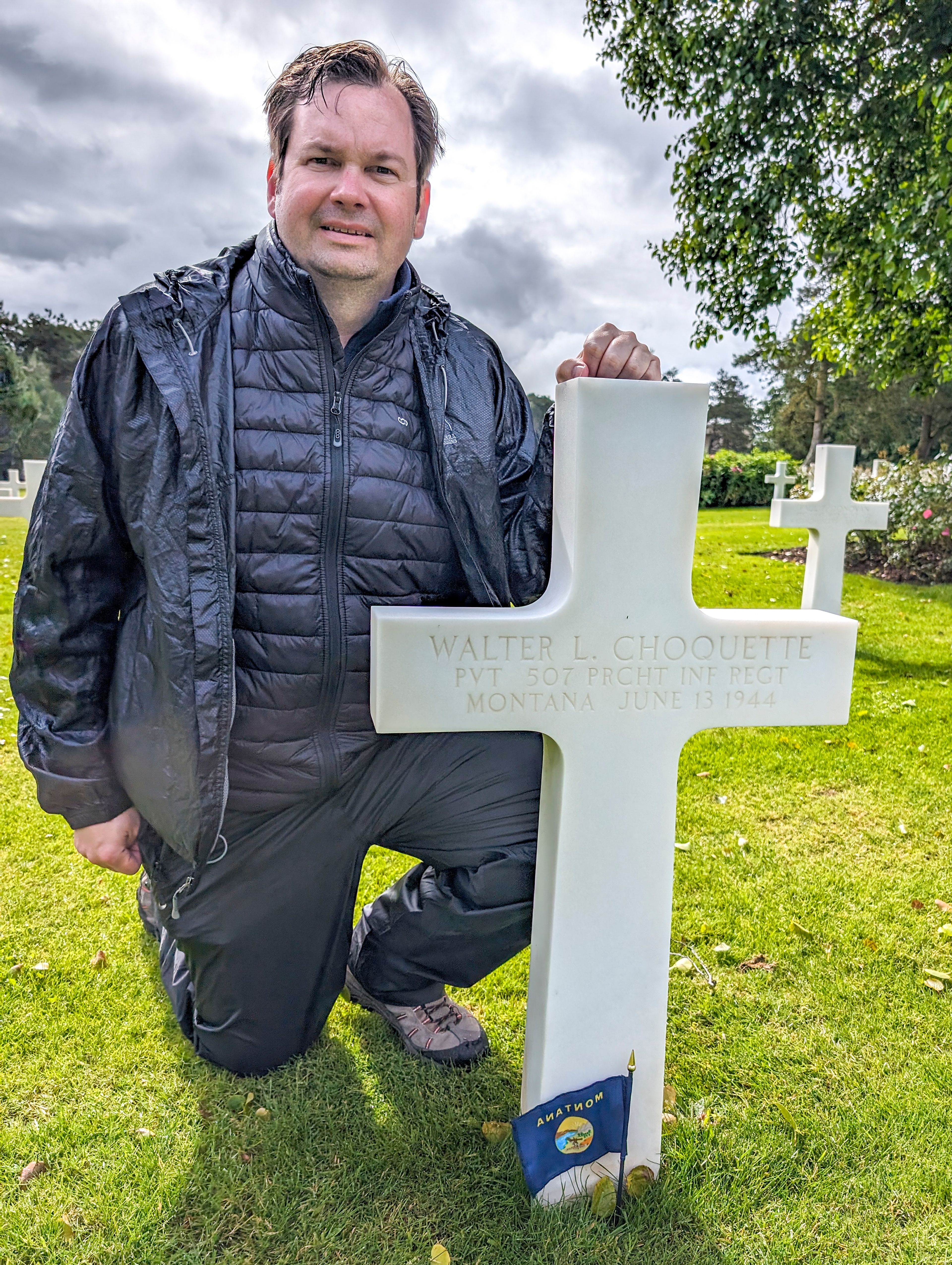 Dustin Johnson kneels beside the grave of Walter Choquette at the Normandy American Cemetery in France.